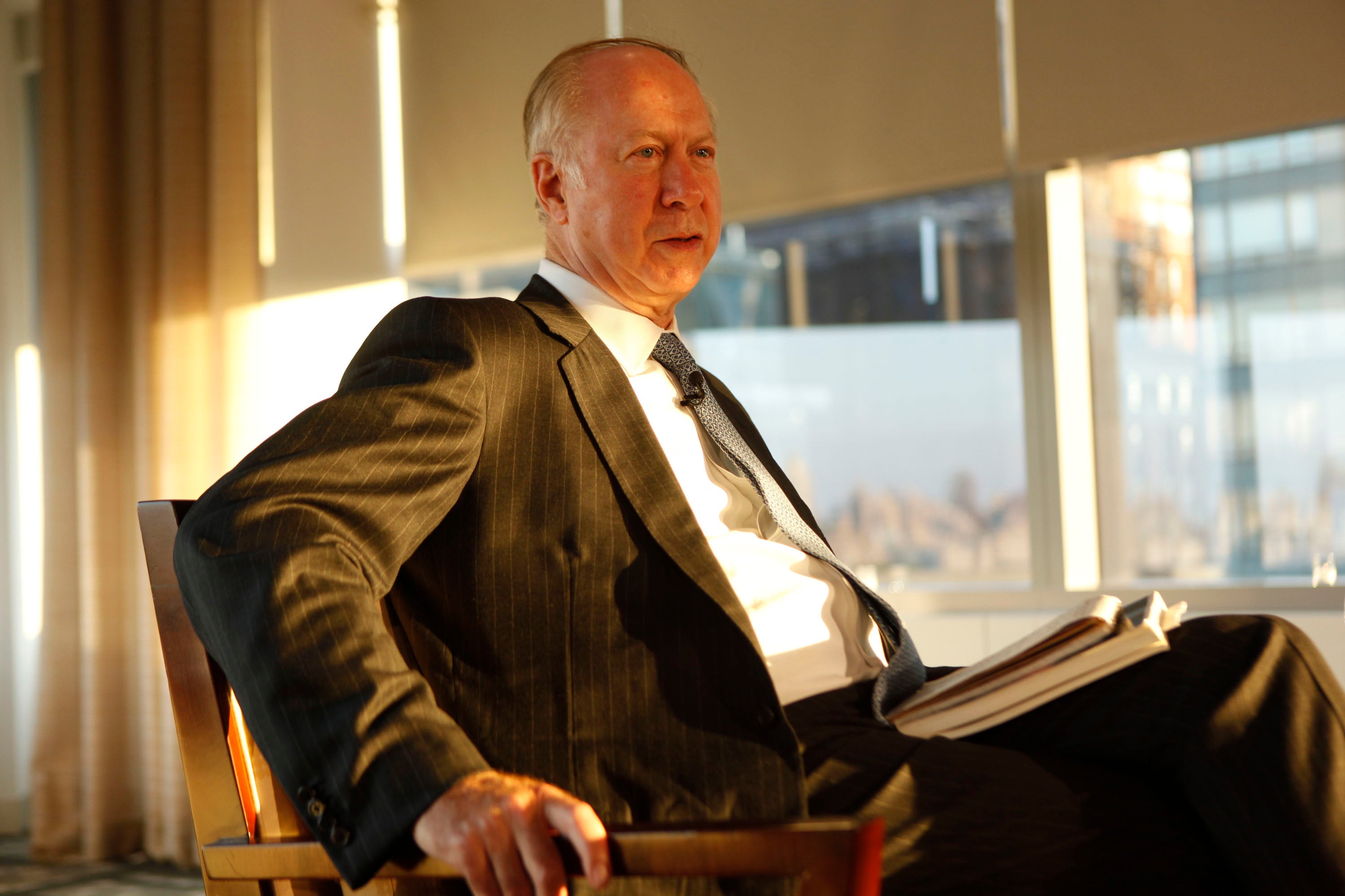 Gergen, wearing a suit, is seated in a chair in a sunny room.