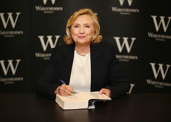 Former US Secretary of State Hillary Clinton signs copies of her
