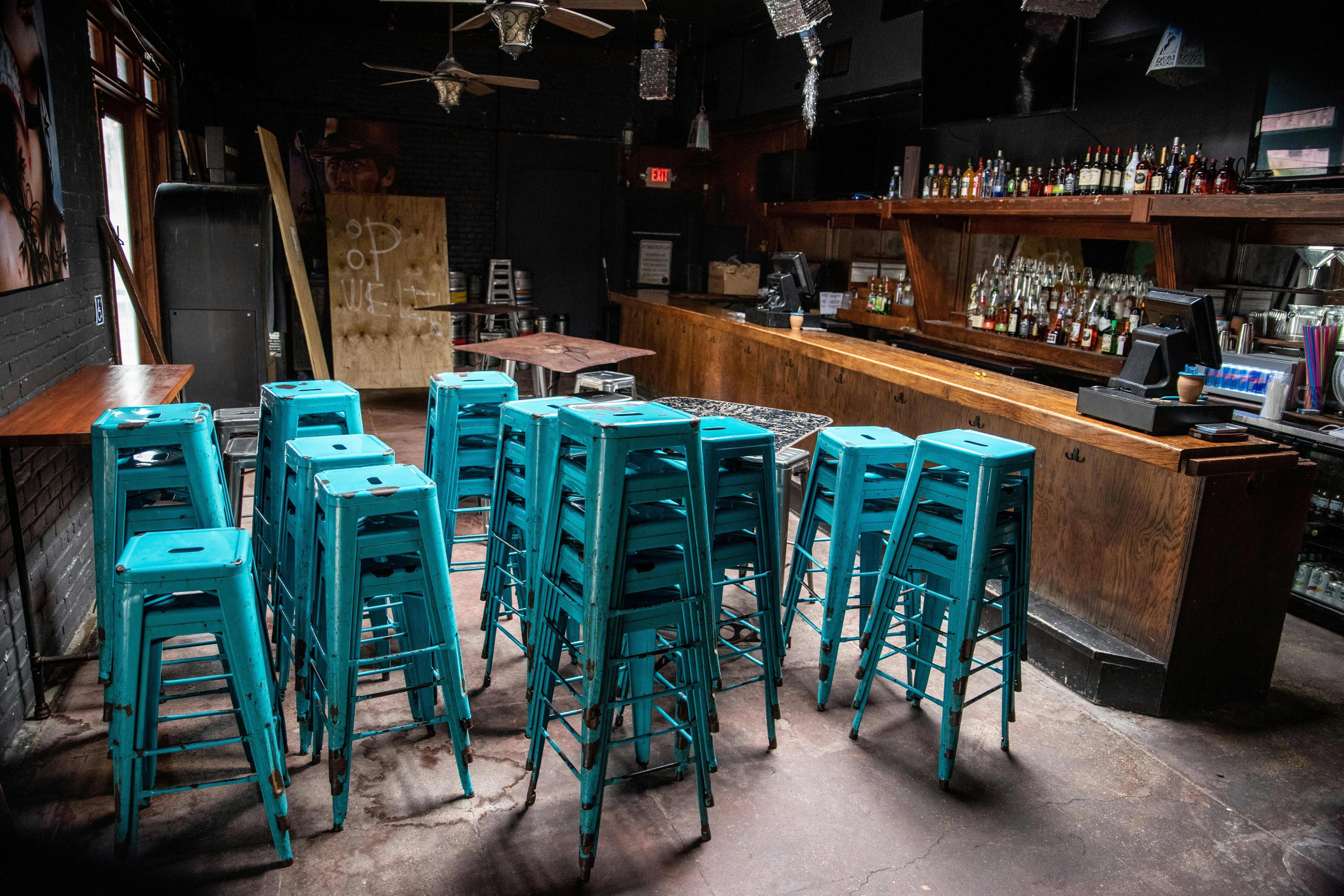 Chairs sit stacked inside a closed bar.