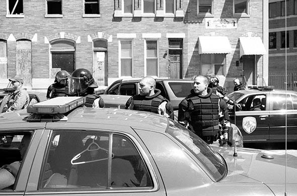 Three police officers look in the direction of a noise from down the street. It was nothing in particular. Baltimore.