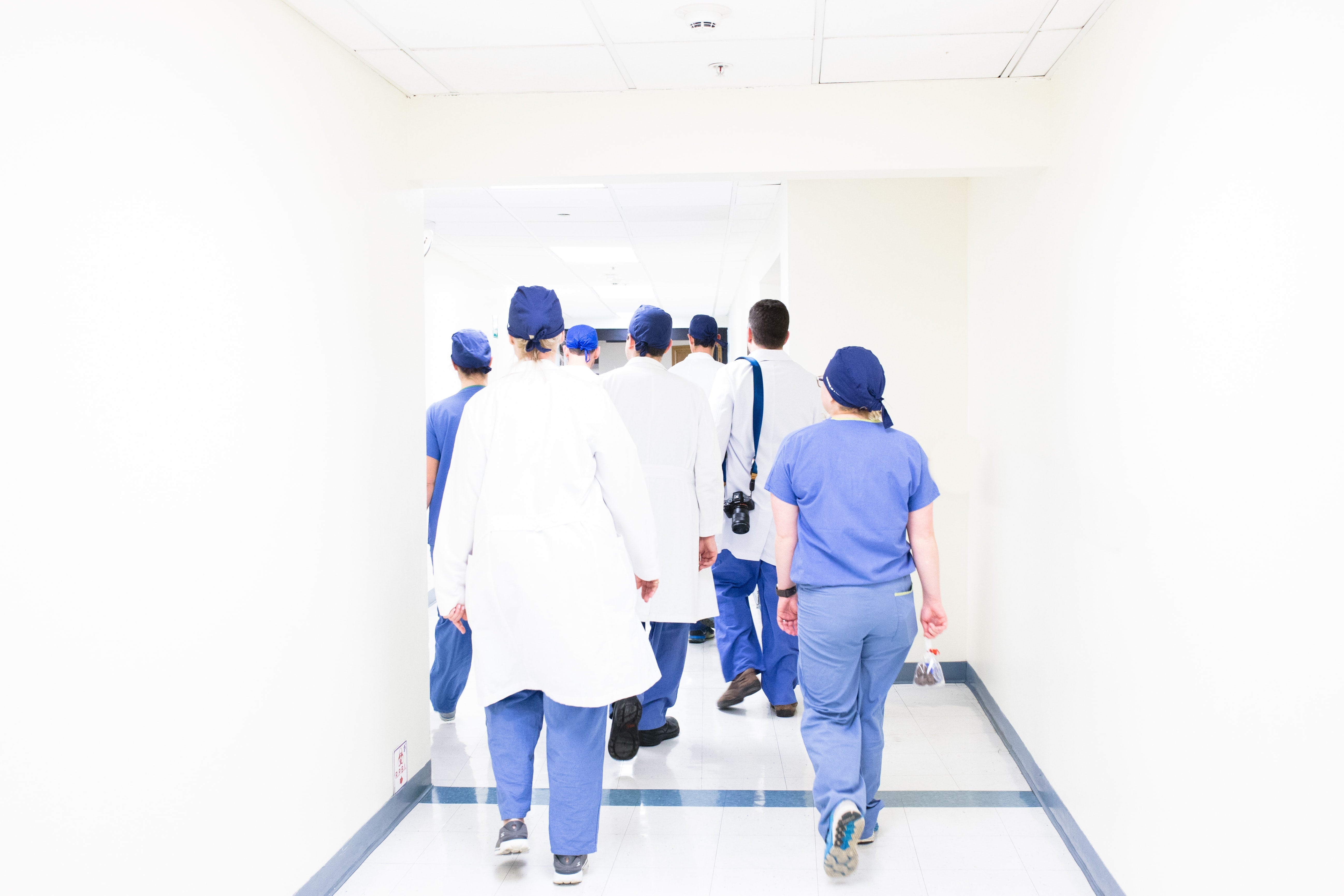 Doctors walking down a hallway with their backs turned.