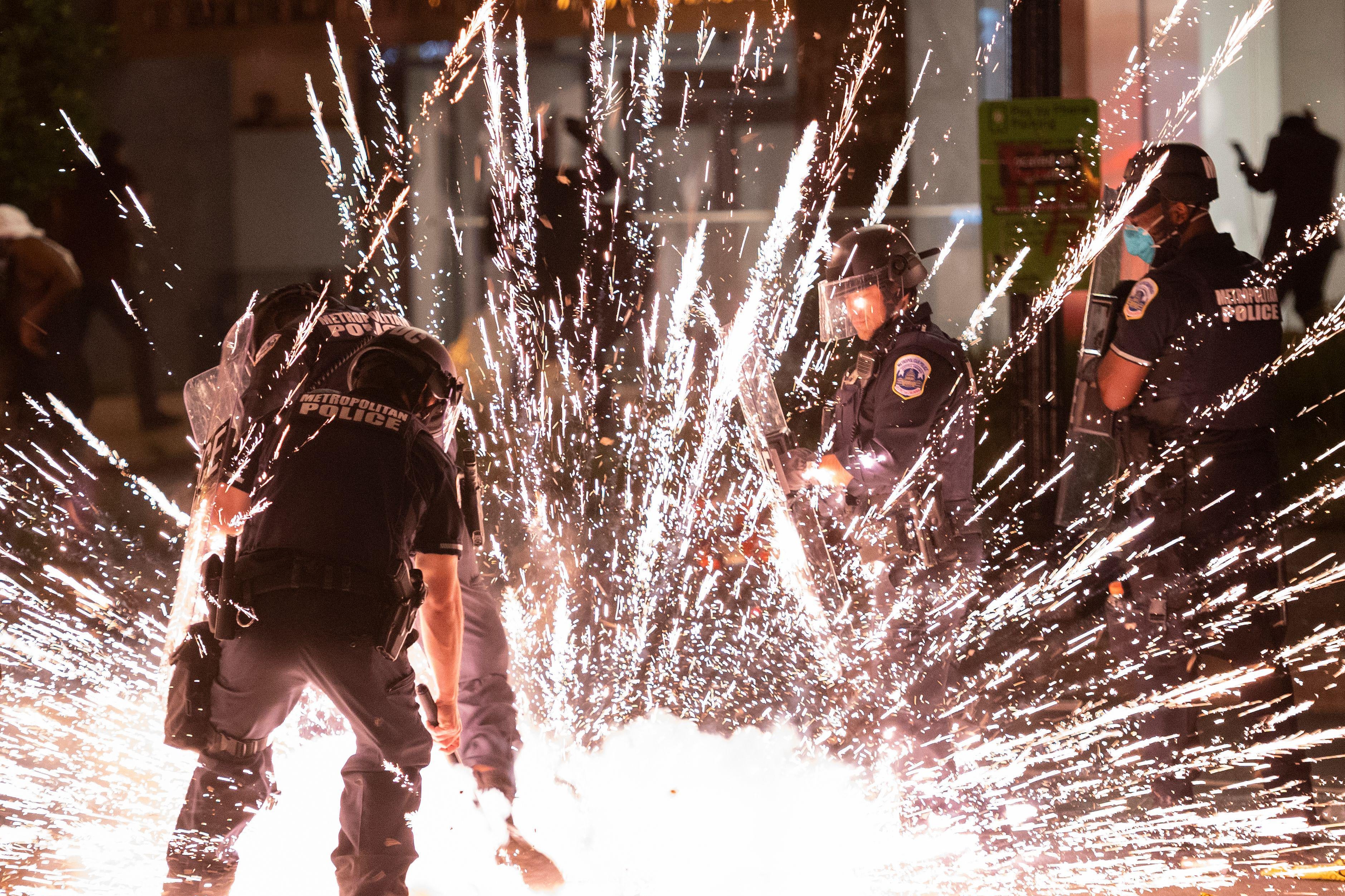 A firecracker thrown by protesters explodes under police one block from the White House on May 30, 2020 in Washington, D.C.