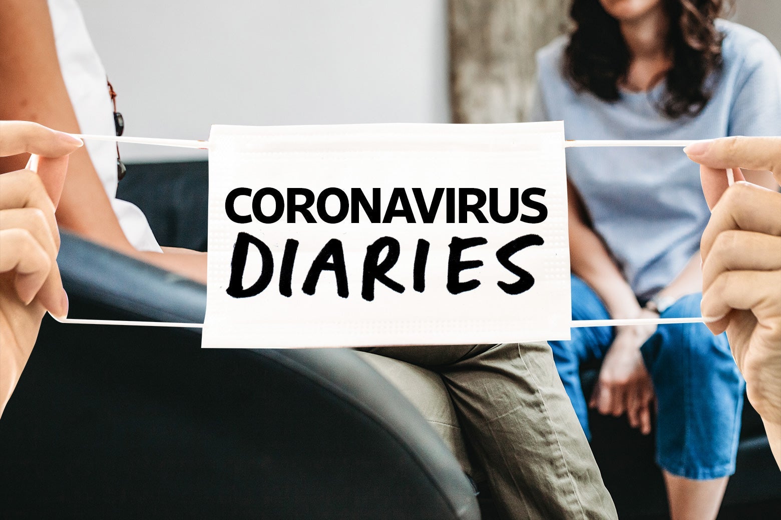 Two women sit behind hands holding a surgical mask that says "Coronavirus Diaries."