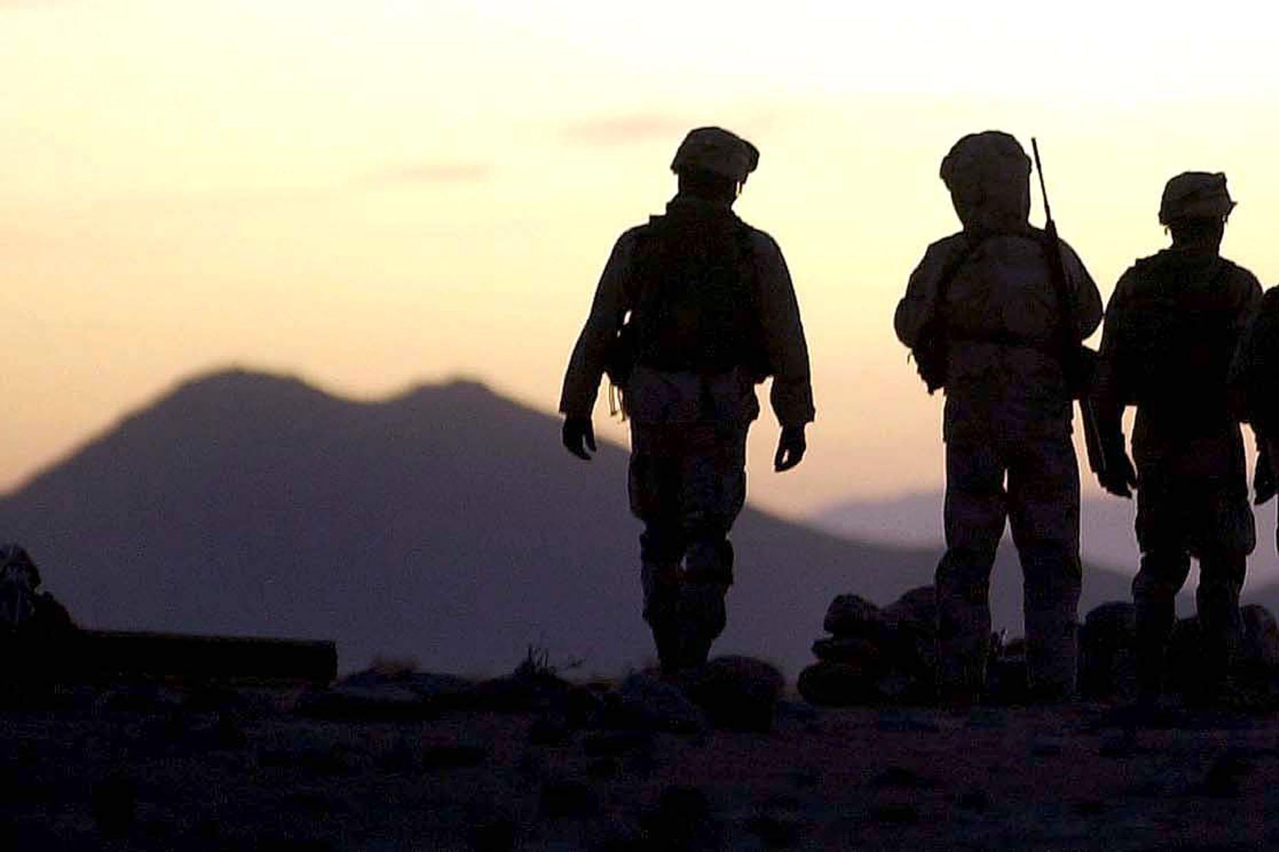 U.S. soldiers in silhouette on a hilltop in Afghanistan.