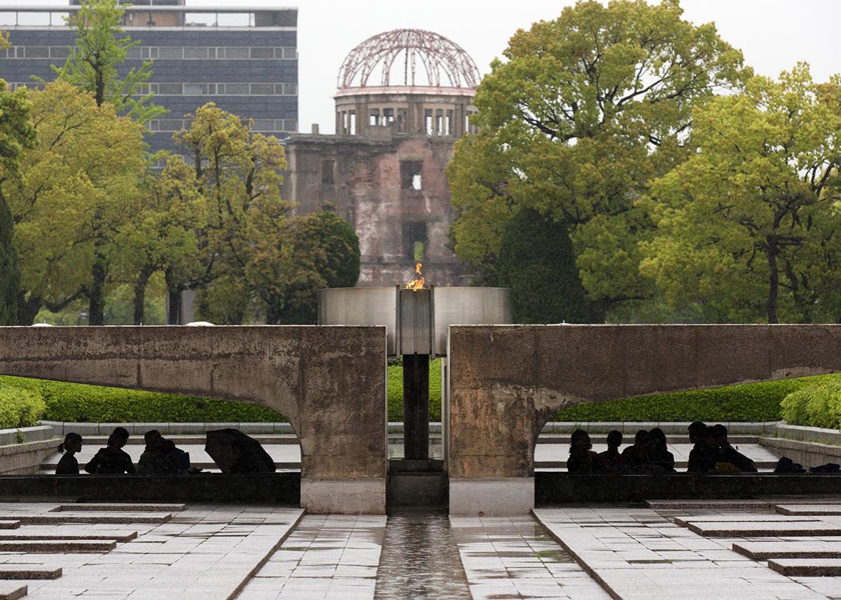 Visitors shelter from the rain under the Peace Flame as they visit the Memorial Park and the nearby Hiroshima Peace Memorial Museum on April 21, 2016 in Hiroshima, Japan. 
