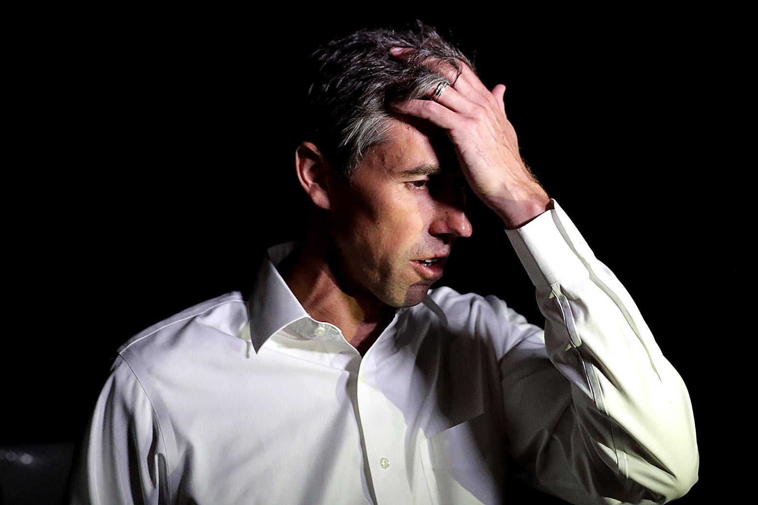 Beto O'Rourke holds a hand to his forehead while he talks with reporters after a day of door-to-door canvassing on Nov. 3 in Dallas.