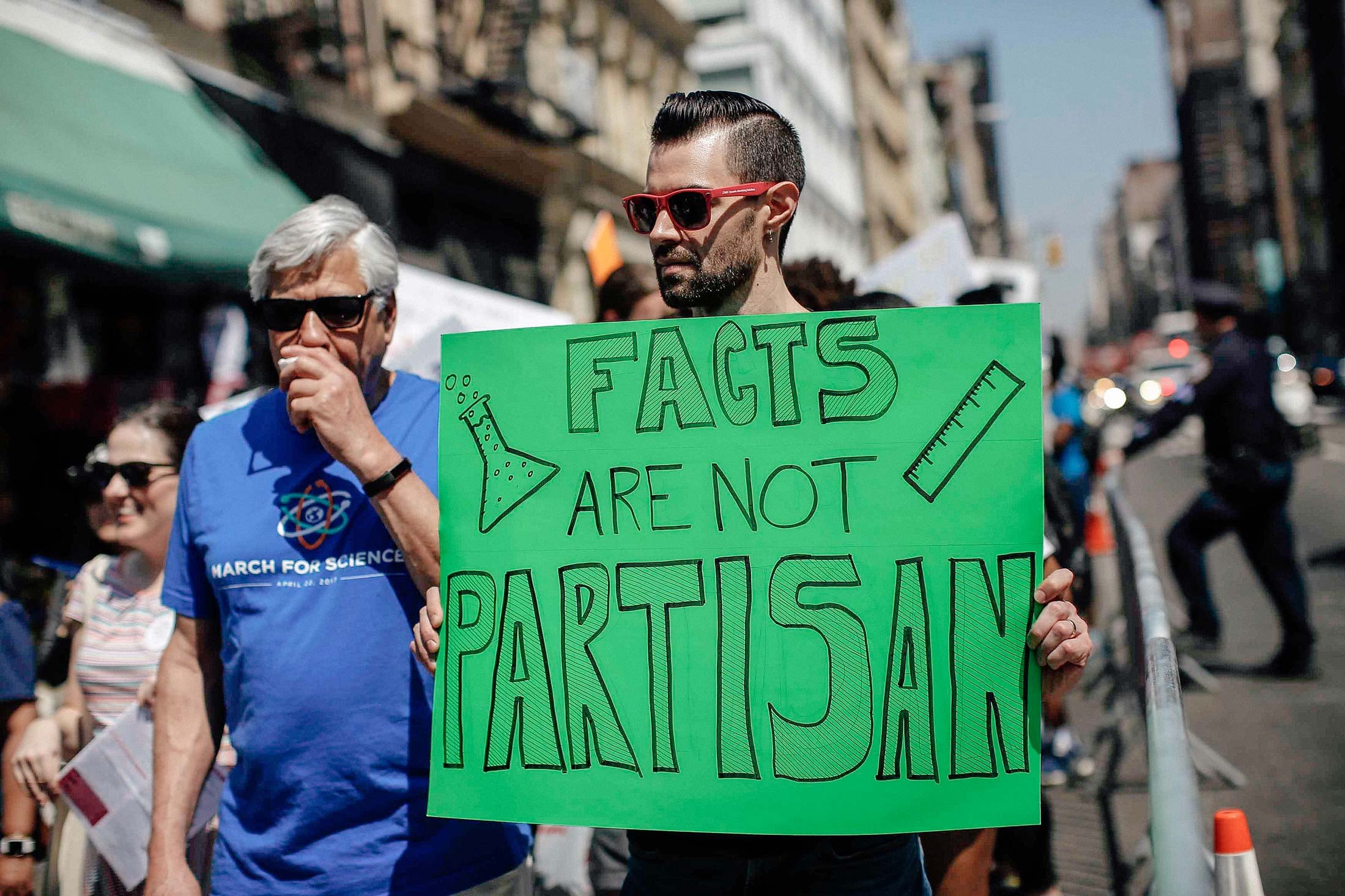 A man carrying a poster reading Facts are not Partisan at a march in New York City.
