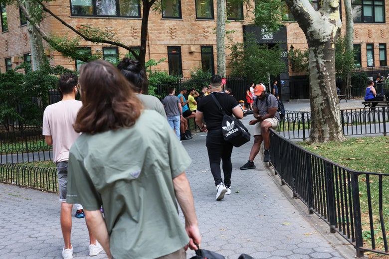 A line with someone in a light green shirt at the end craning their neck to see how far it extends. No faces are visible.