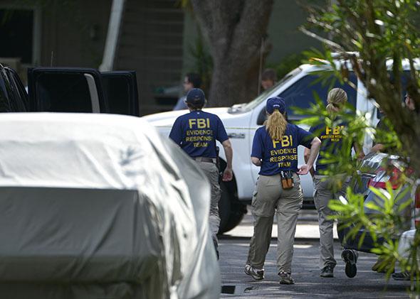 FBI personnel walk through the complex surrounding the apartment