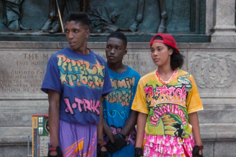 Three people standing together in colorful clothing.