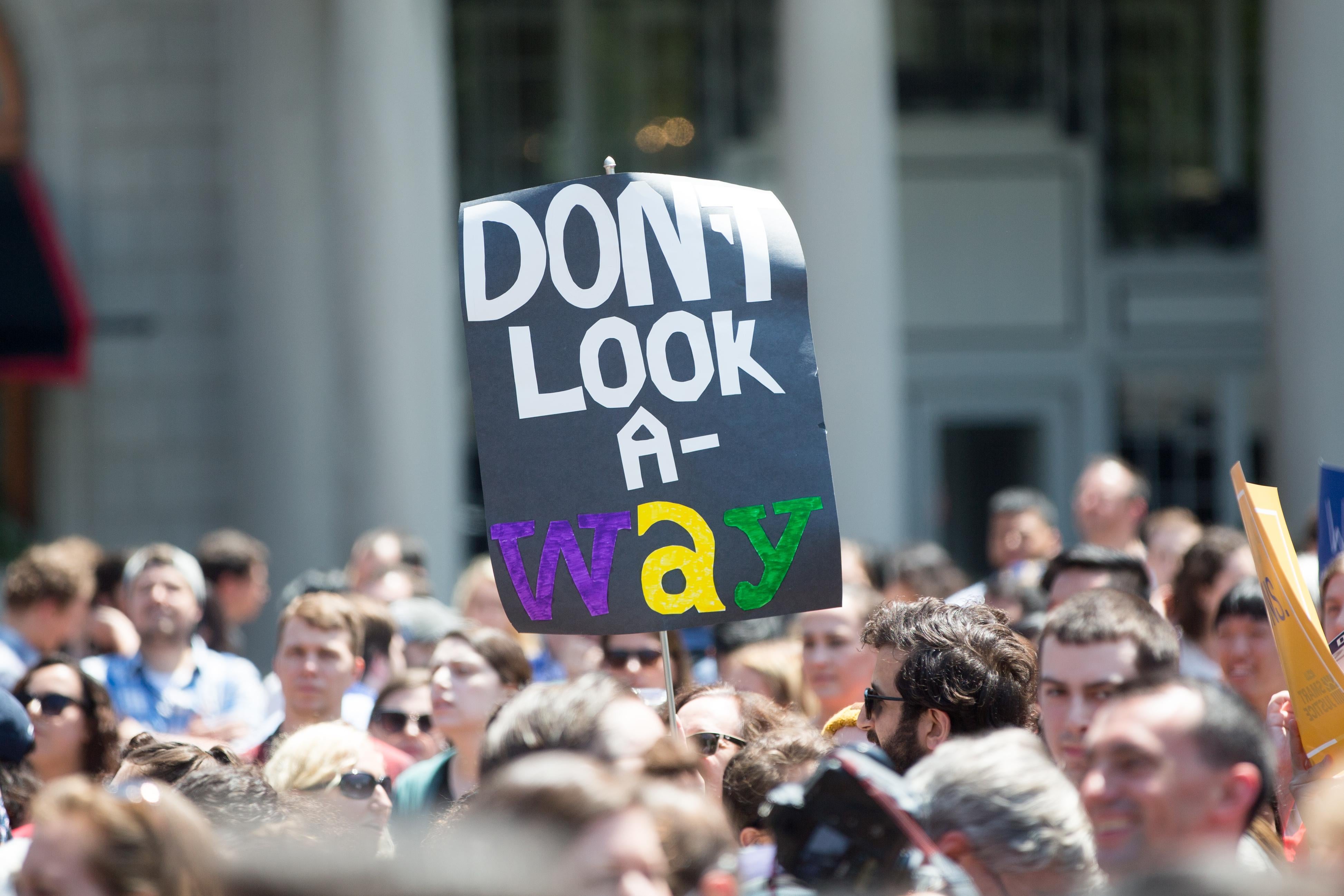A protestor holds a handmade "Don't Look Away" sign in Copley Square in Boston.