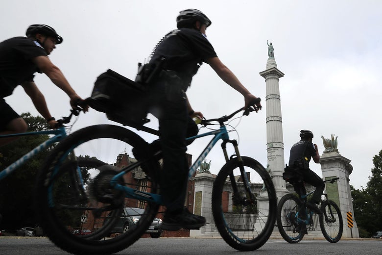 Police officers patrol on bicycles past the Jefferson Davis Monument in Richmond, Virginia.