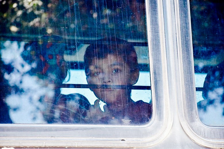 A child looks through the window of a bus carrying migrants near McAllen, Texas, on Saturday.