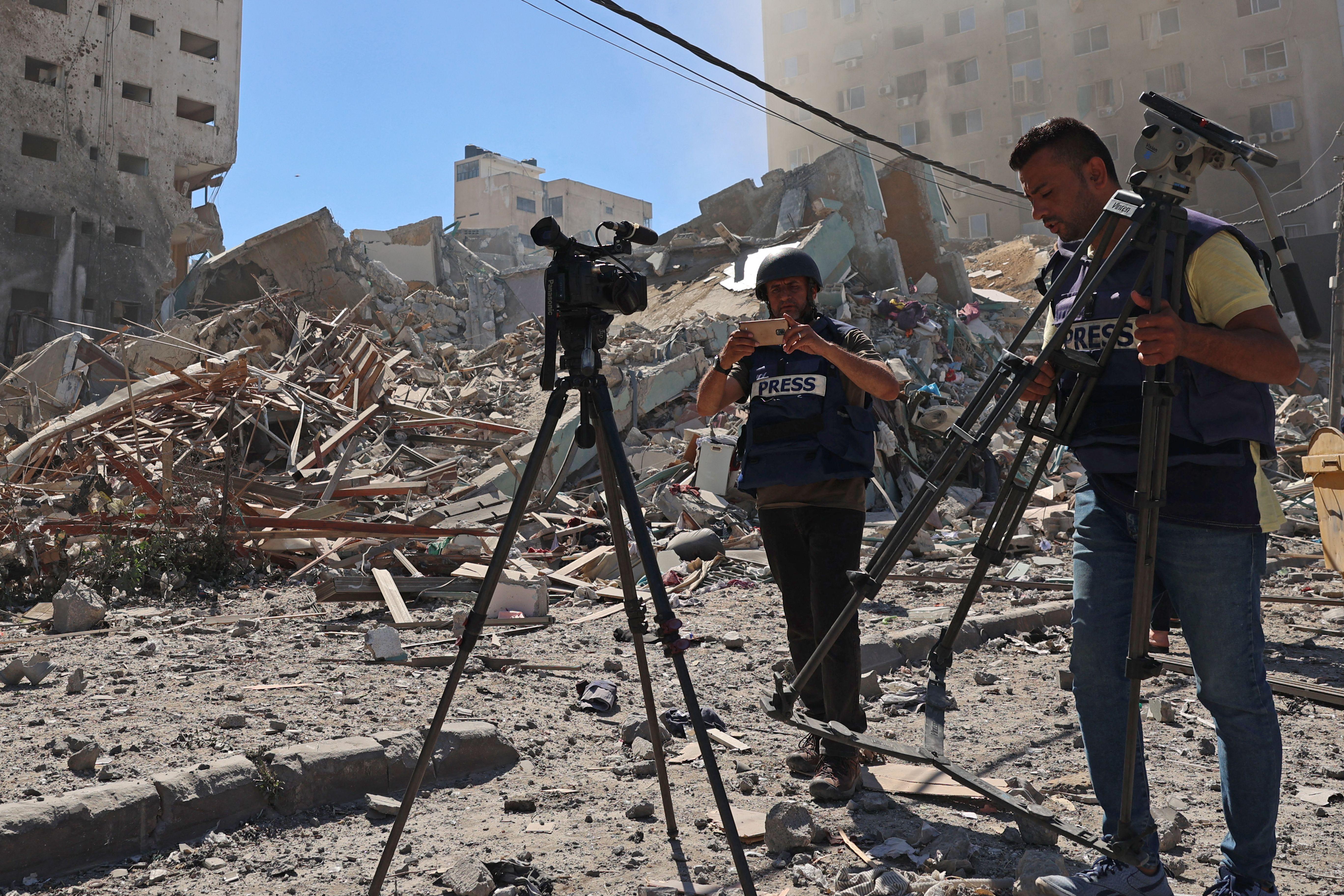 Journalists stand next to the rubble of Jala Tower, which housed international press offices, following an Israeli airstrike in the Gaza Strip on May 15, 2021.