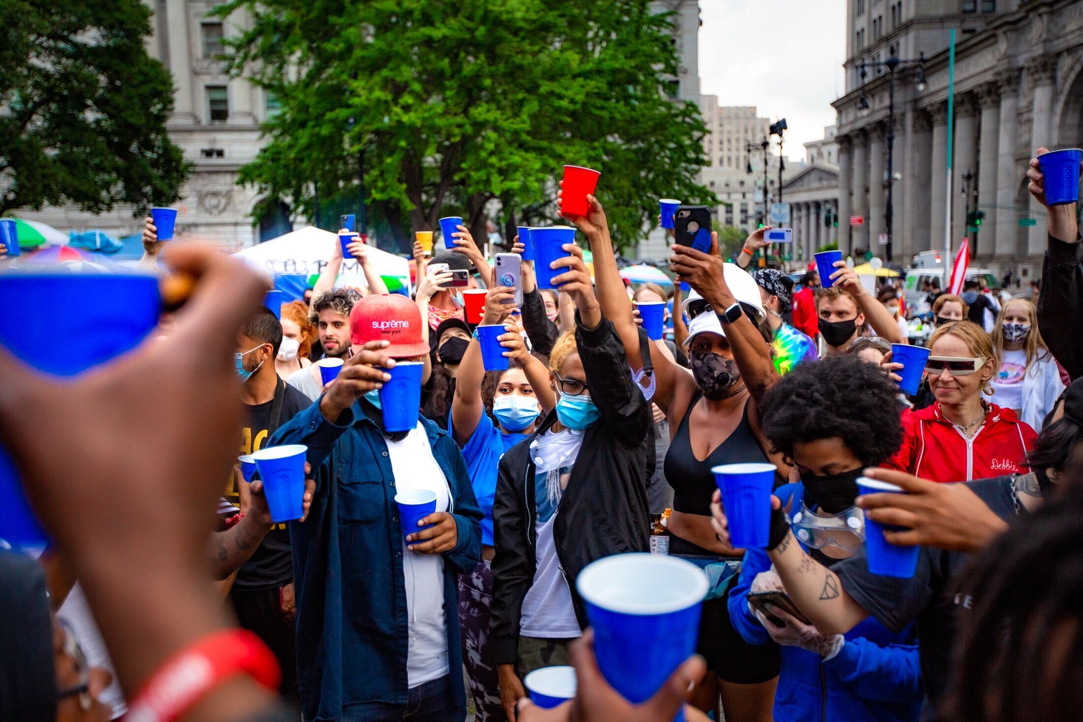 Protesters raise red and blue plastic cups in a toast at Occupy City Hall