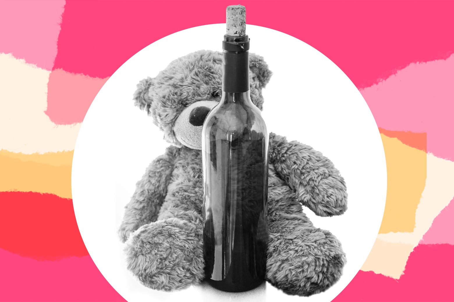 A teddy bear hugs a bottle of red wine.