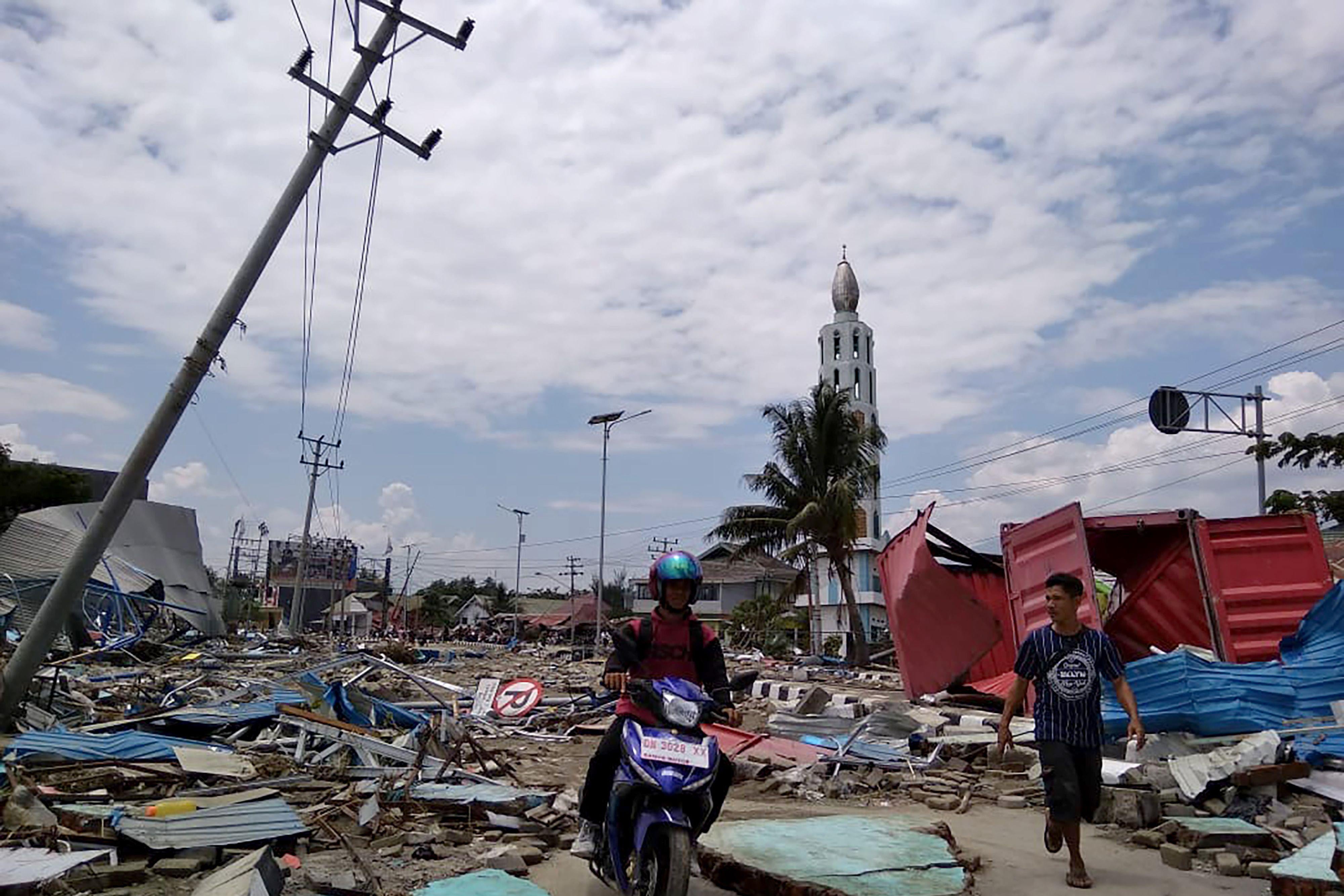 Residents make their way along a street full of debris after an earthquake and tsunami hit Palu.