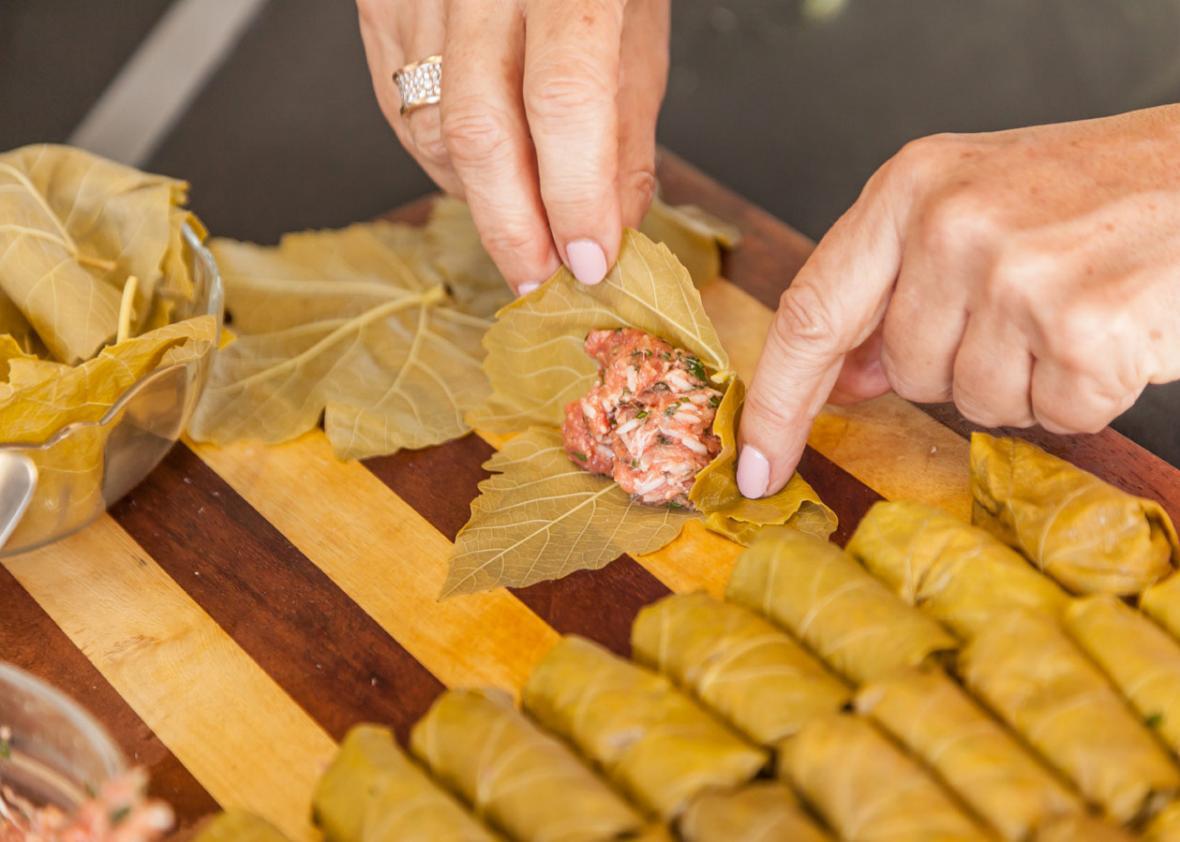 Rolling the meat and rice filling into vine leaves for yaprakes de oja parra kon arros.