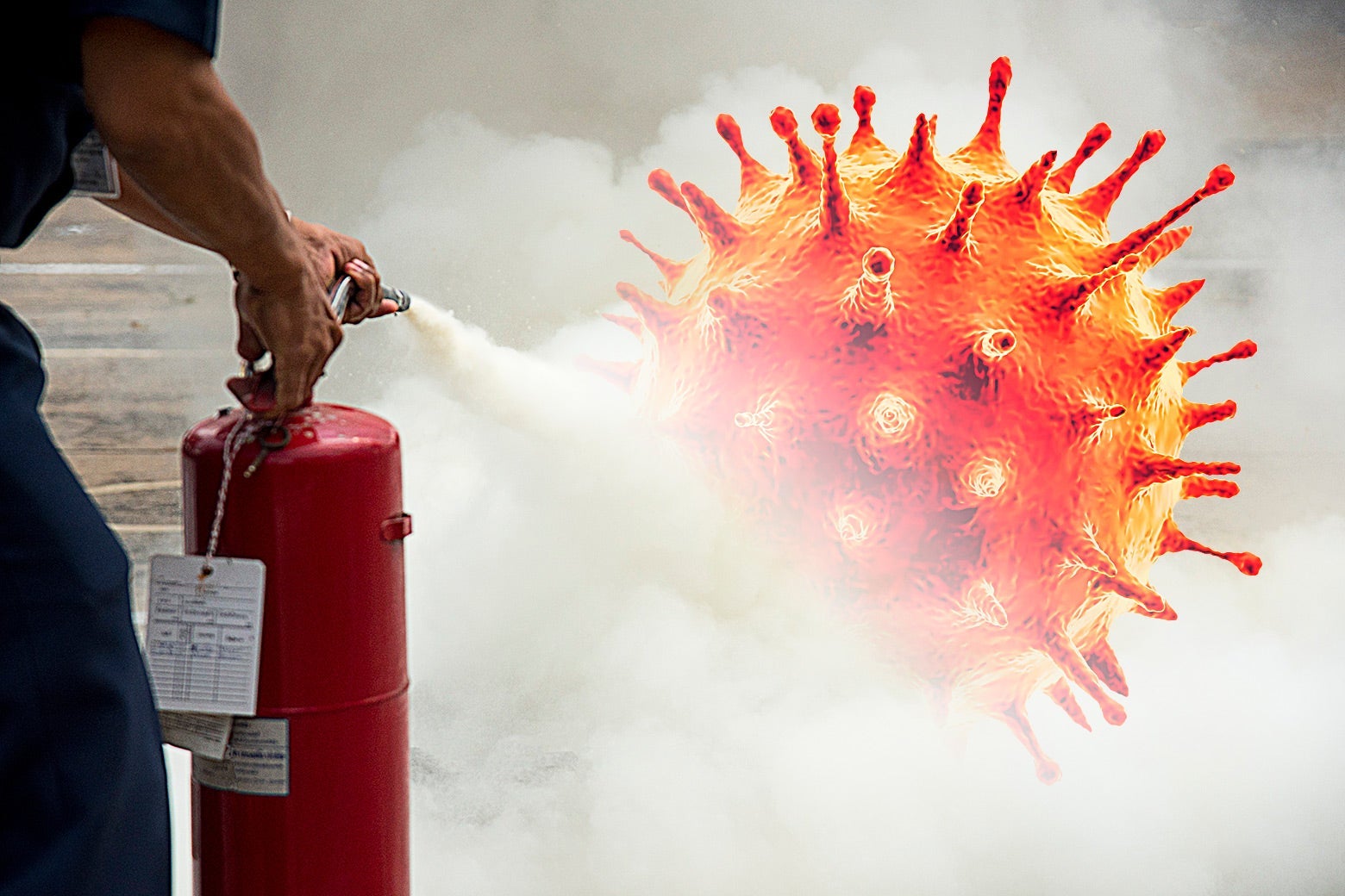 A man spraying a fire extinguisher onto a COVID-19 germ.