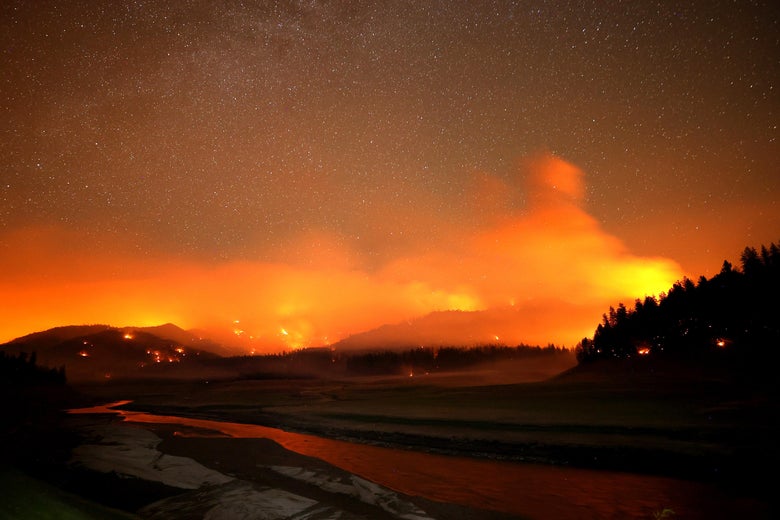 A California wildfire burning orange in hills at night.