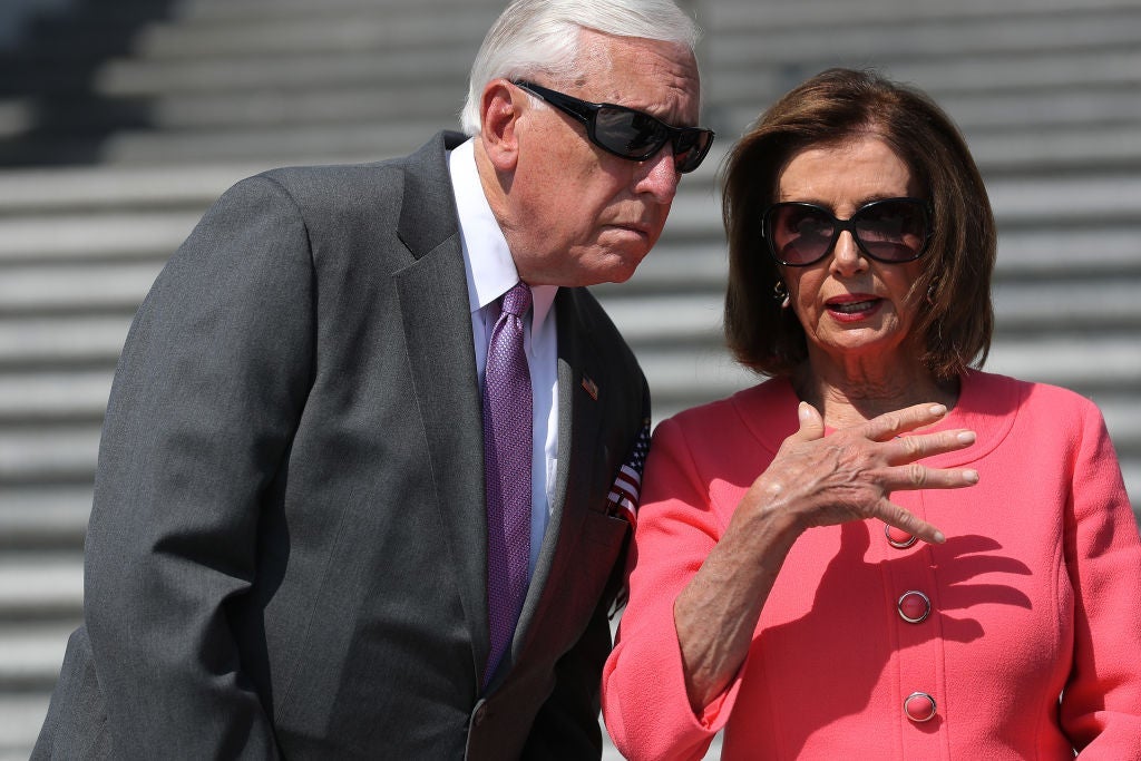 Hoyer, wearing sunglasses, leans over to listen to Pelosi, who is also wearing sunglasses.