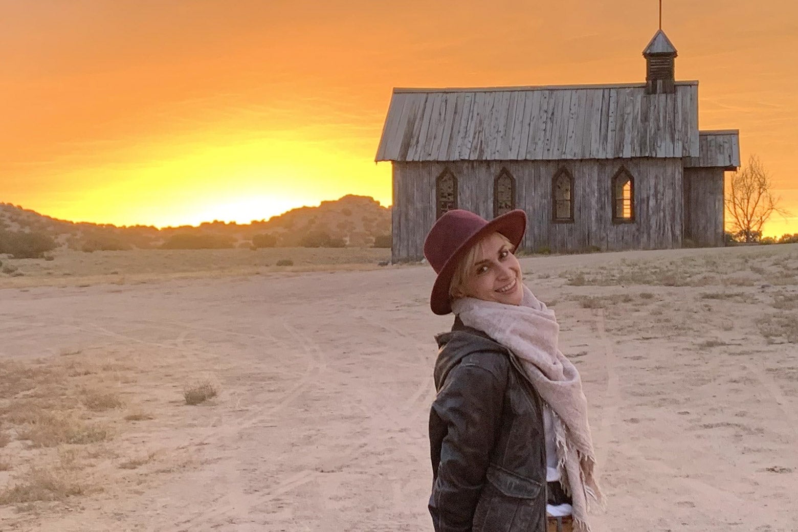 Halyna Hutchins smiles in front of an old church at sunset in a still from the documentary. 