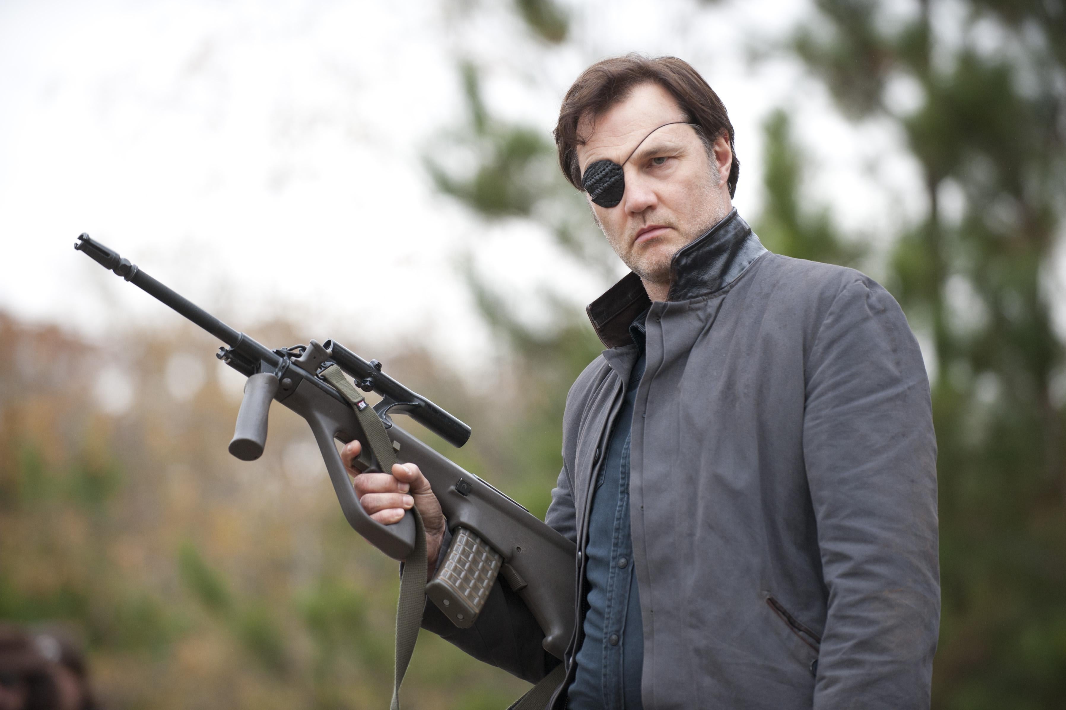 A man in an eye patch holds a rifle.