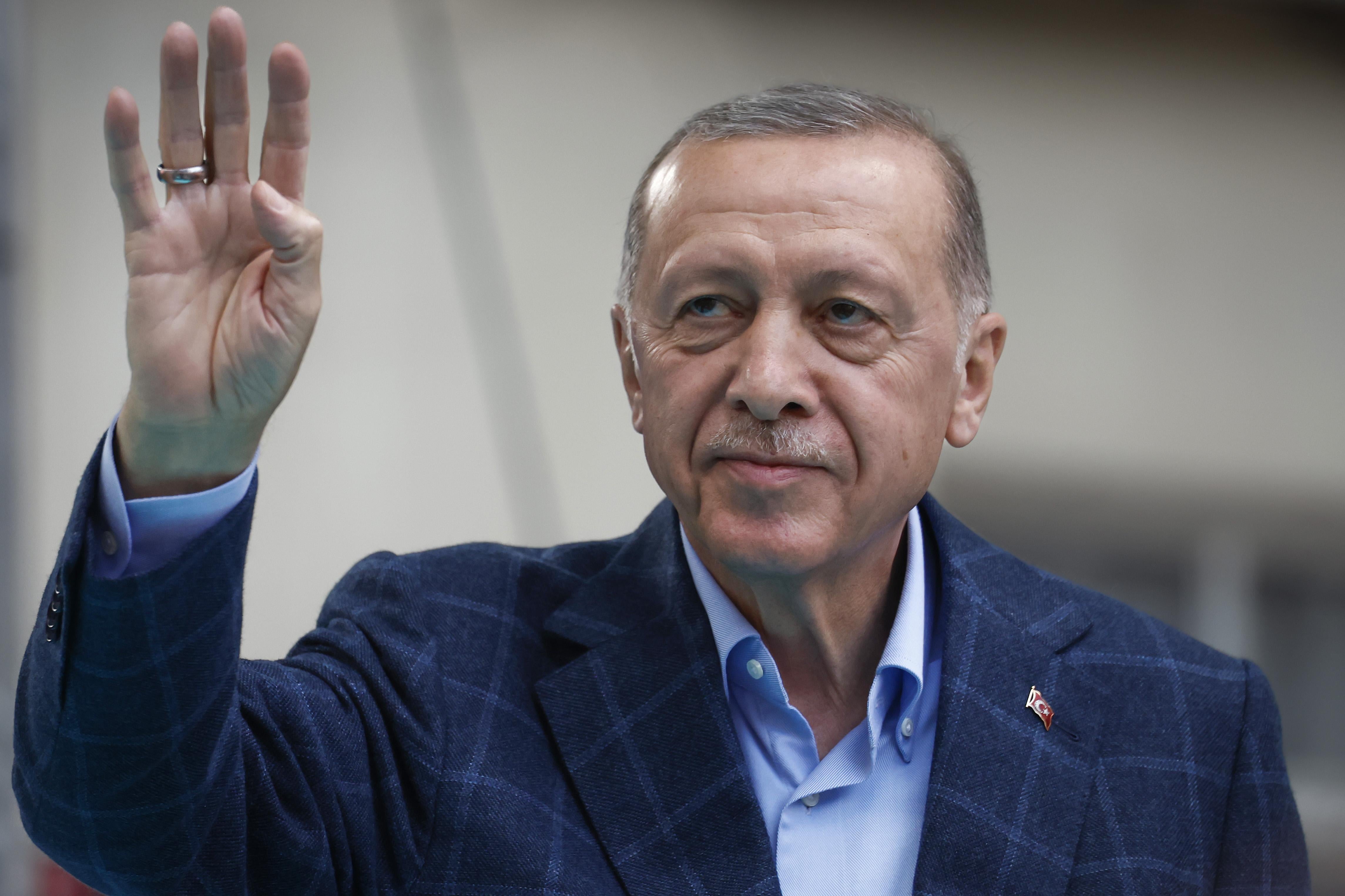 Recep Tayyip Erdogan waves his right hand.