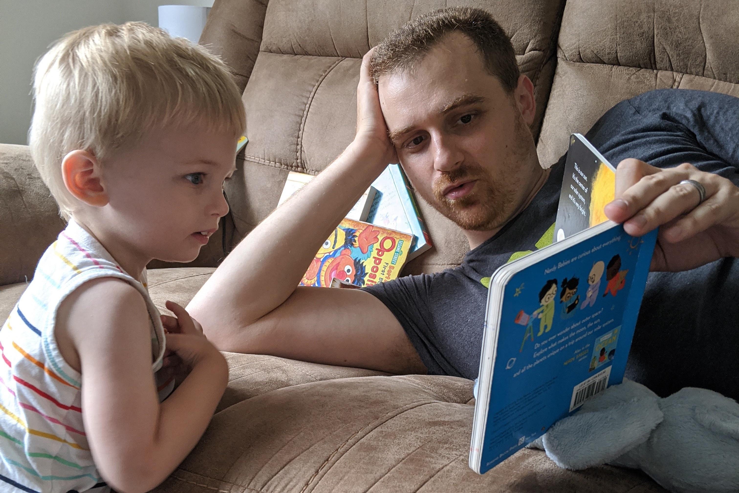 A man reads a children's book to his small child.
