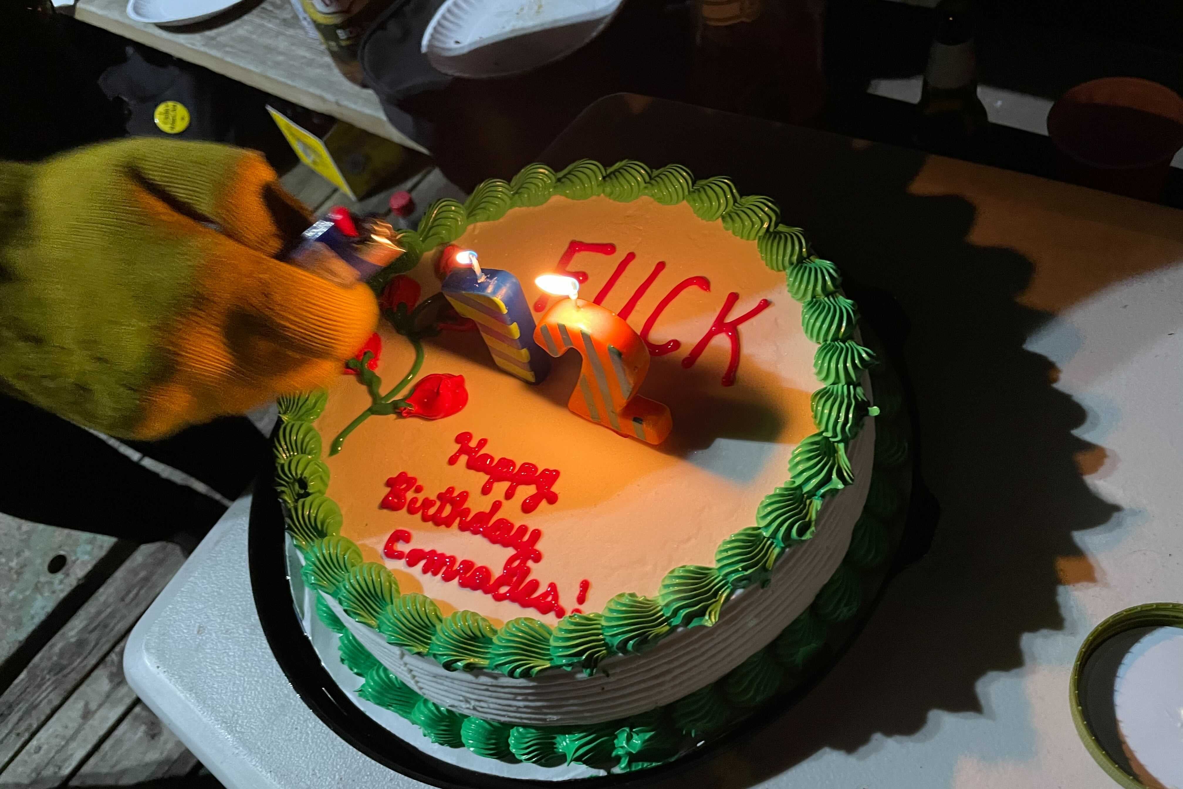 A birthday cake reads "Fuck 12. Happy birthday, comrades." 
