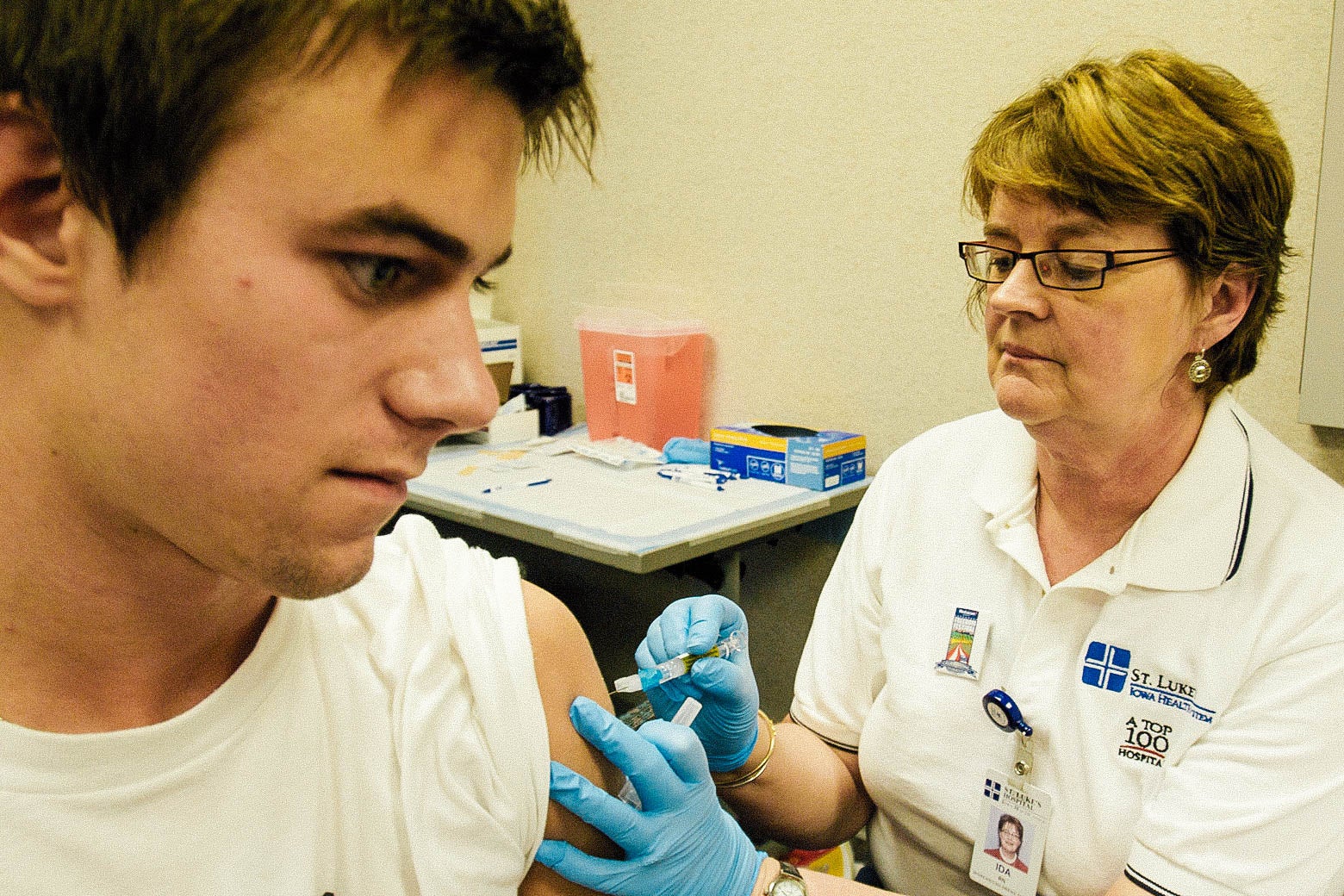 A young man receives a tetanus shot in his left arm.