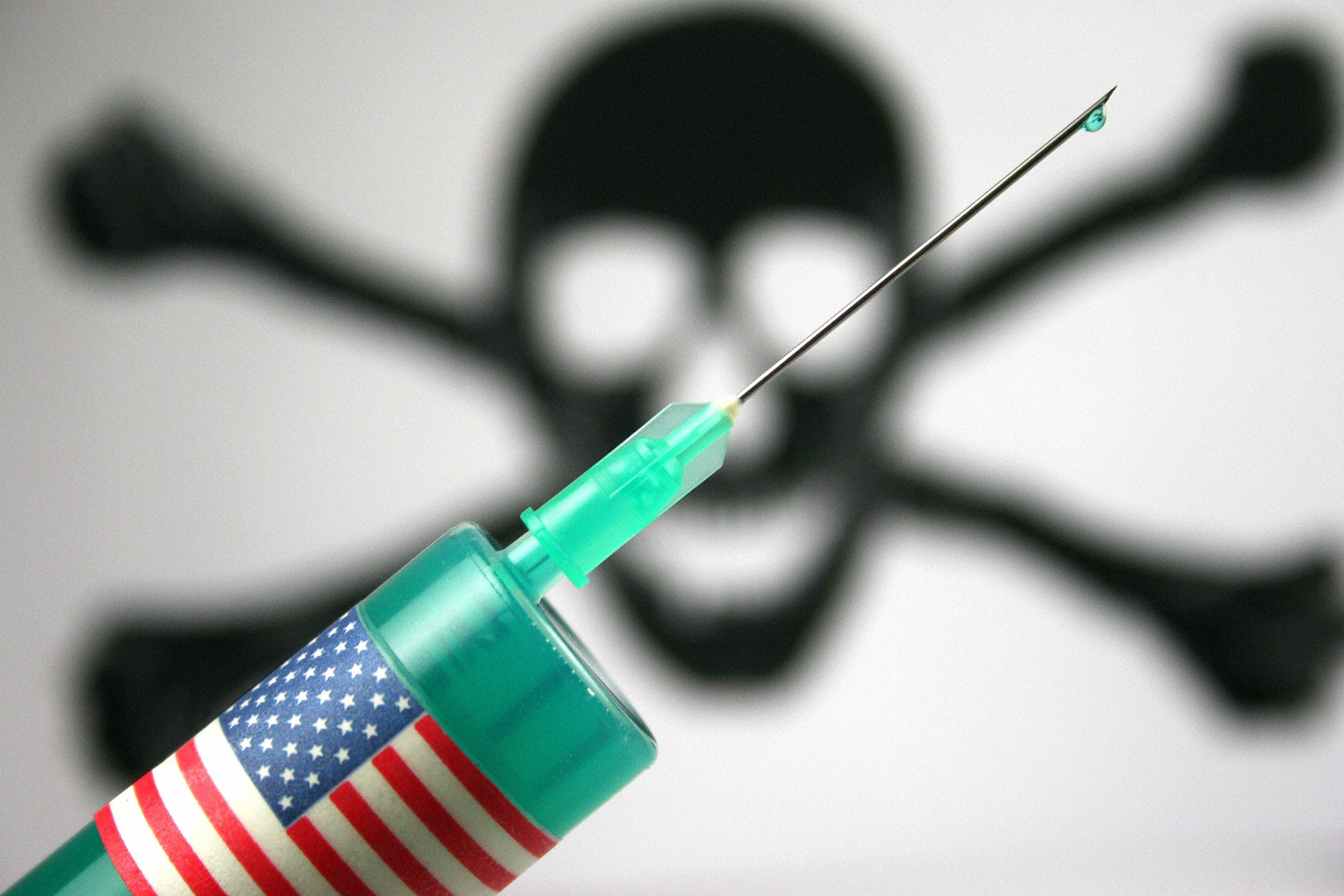 A green syringe, which is used for lethal injections, is wrapped in an American flag sticker.  