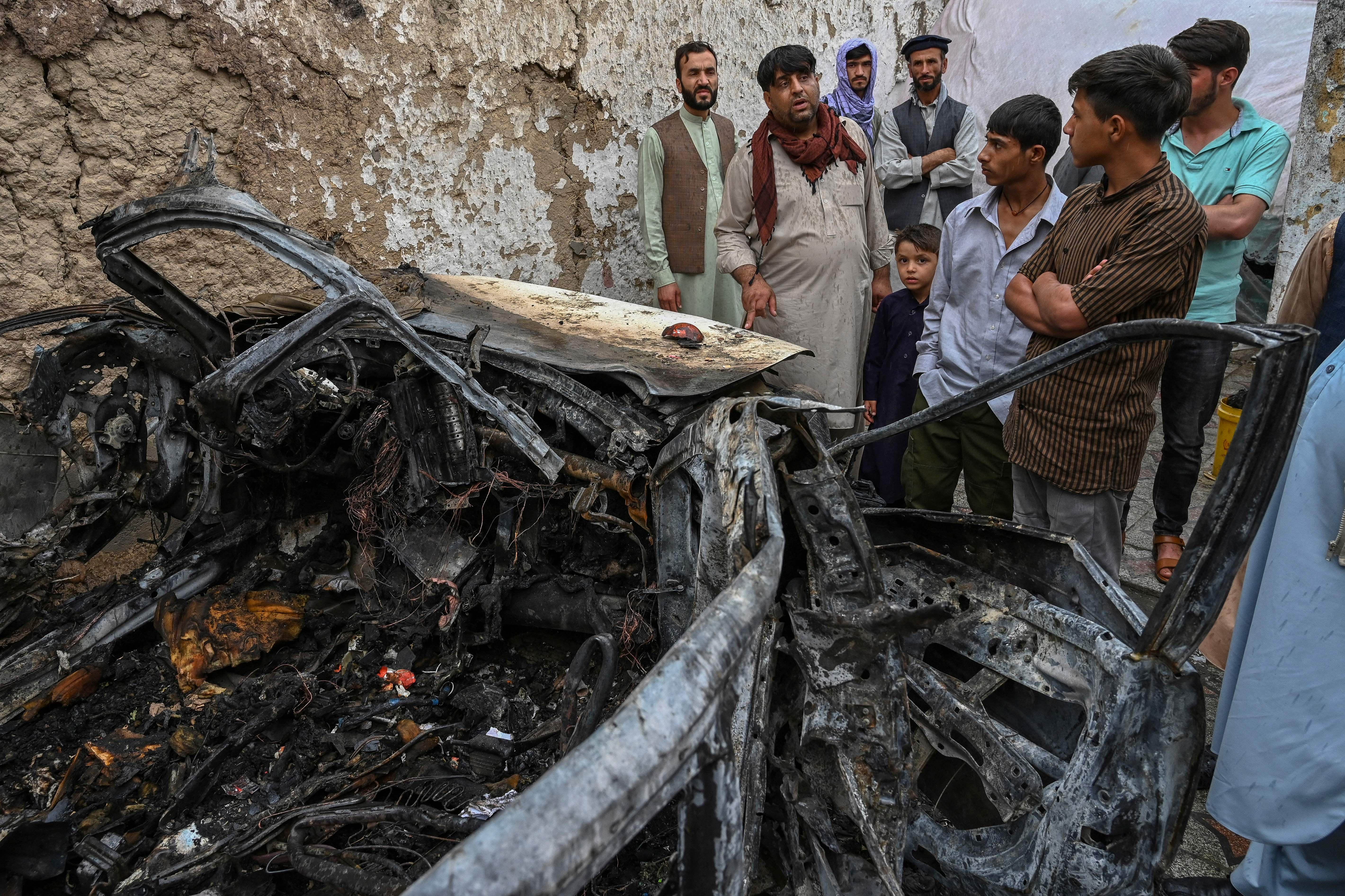 Afghan residents and family members of the victims gather next to a damaged vehicle inside a house, day after a US drone airstrike in Kabul on August 30, 2021. (Photo by WAKIL KOHSAR / AFP) (Photo by WAKIL KOHSAR/AFP via Getty Images)