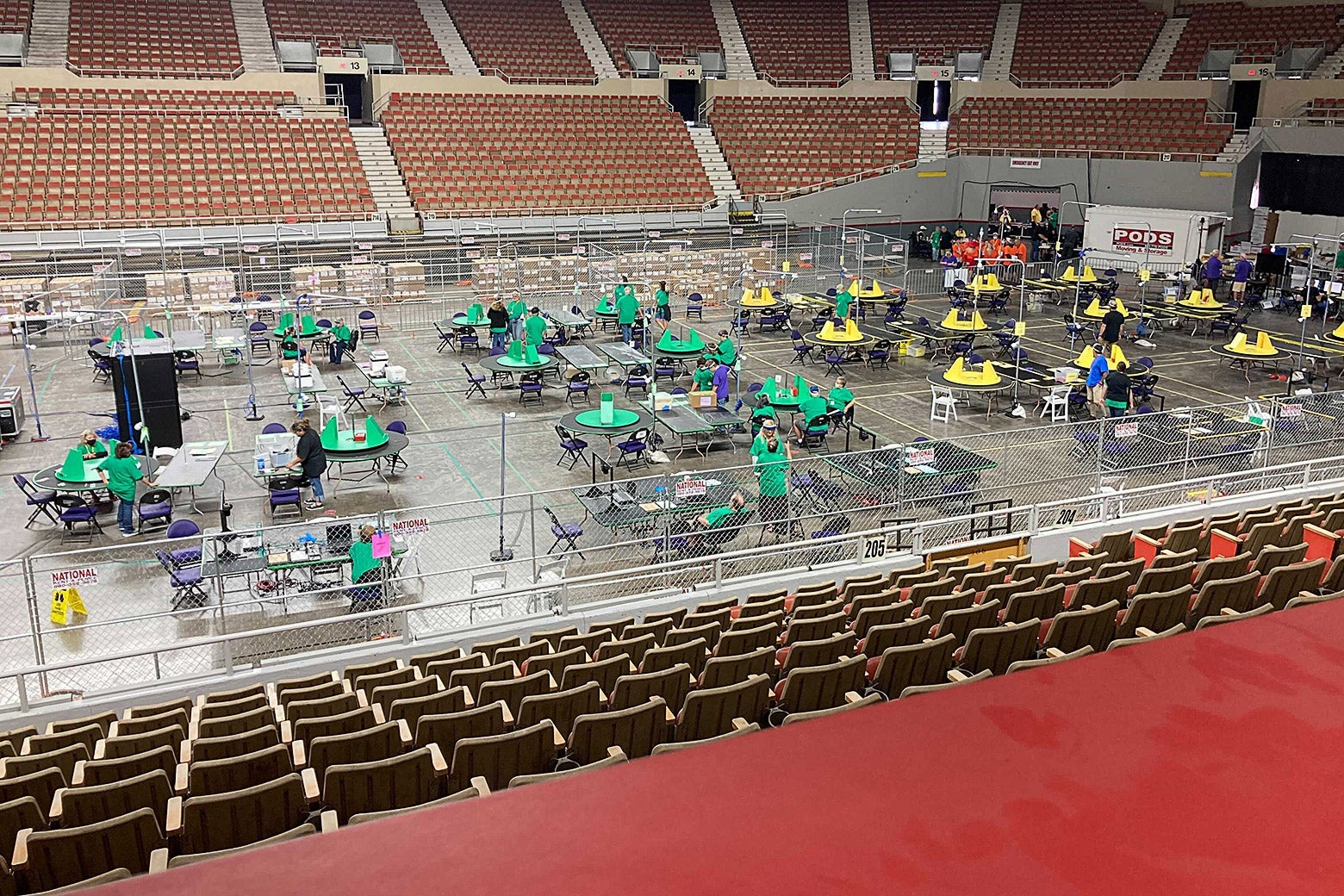 The floor of an arena with color-coded tables on it, seen from the press box.