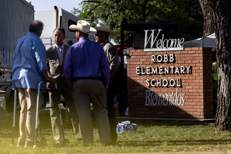 Law enforcement officers standing near the sign for Robb Elementary School.