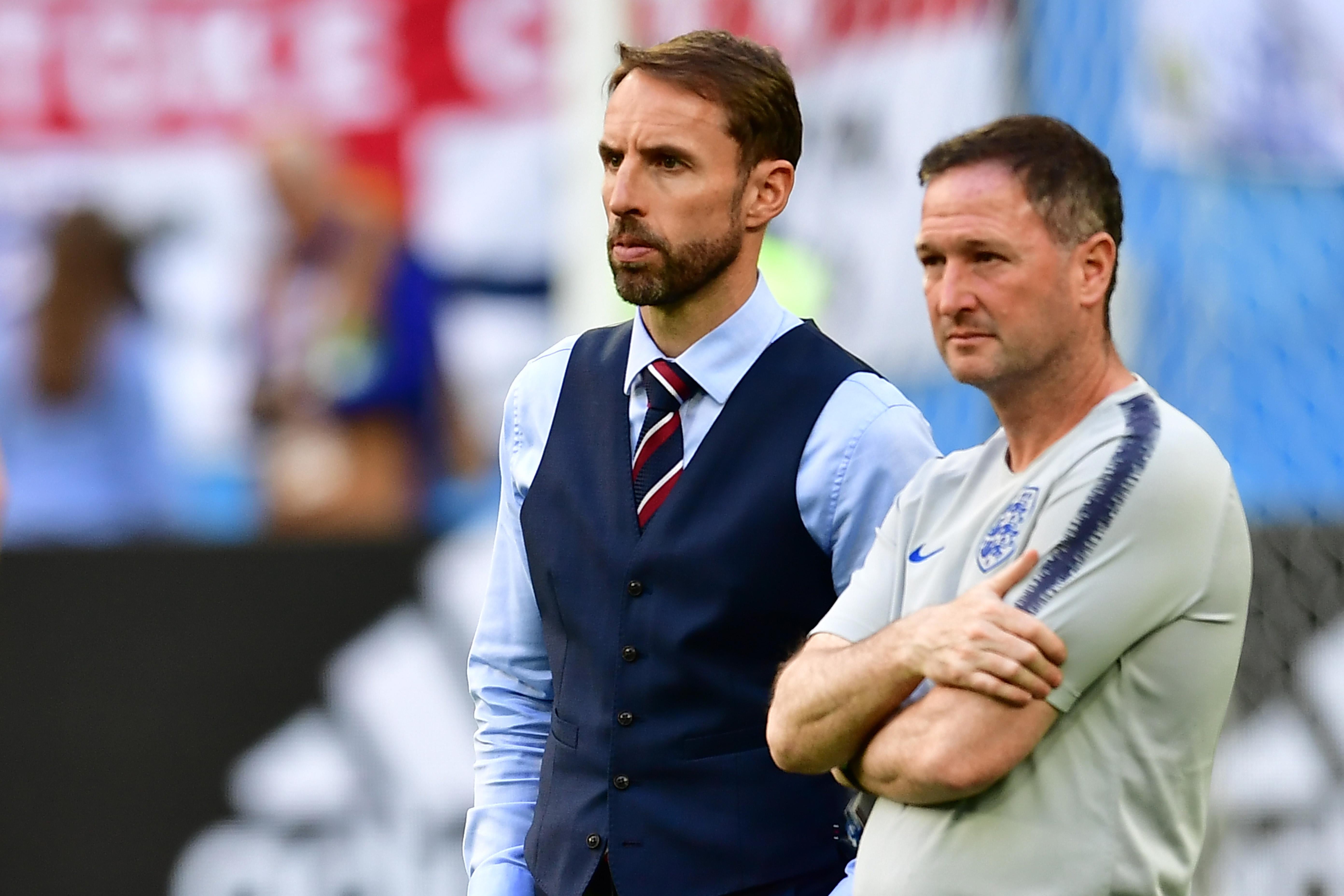 England's coach Gareth Southgate, wearing a vest, and an assistant react to Belgium's victory.