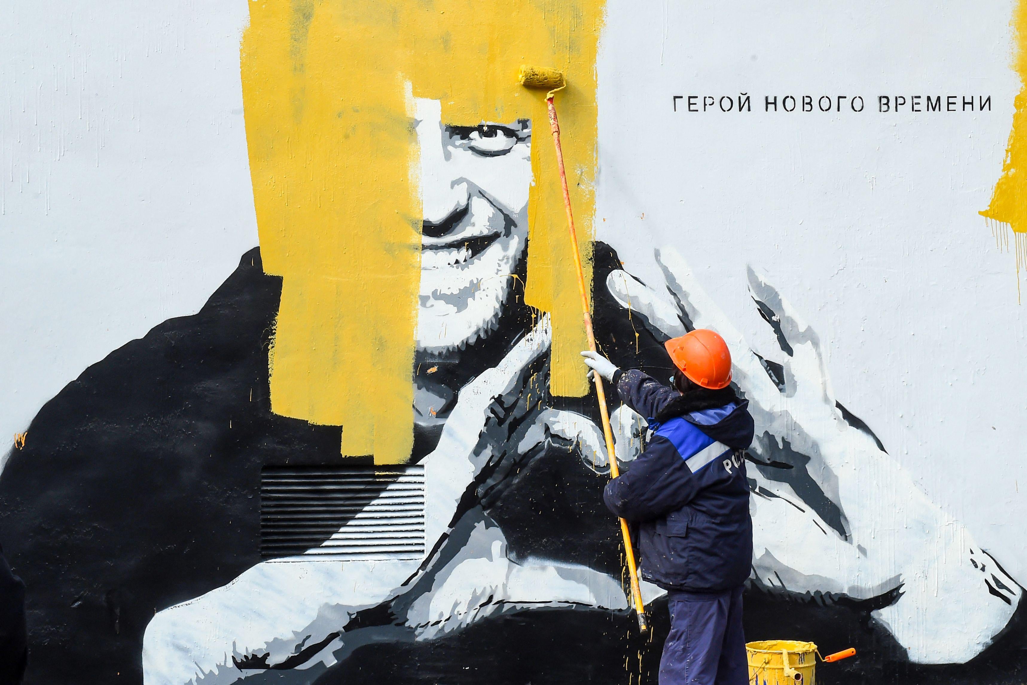 A worker paints over graffiti of jailed Kremlin critic Alexei Navalny in Saint Petersburg on April 28, 2021. The inscription reads: "The hero of the new times". (Photo by Olga MALTSEVA / AFP) (Photo by OLGA MALTSEVA/AFP via Getty Images)