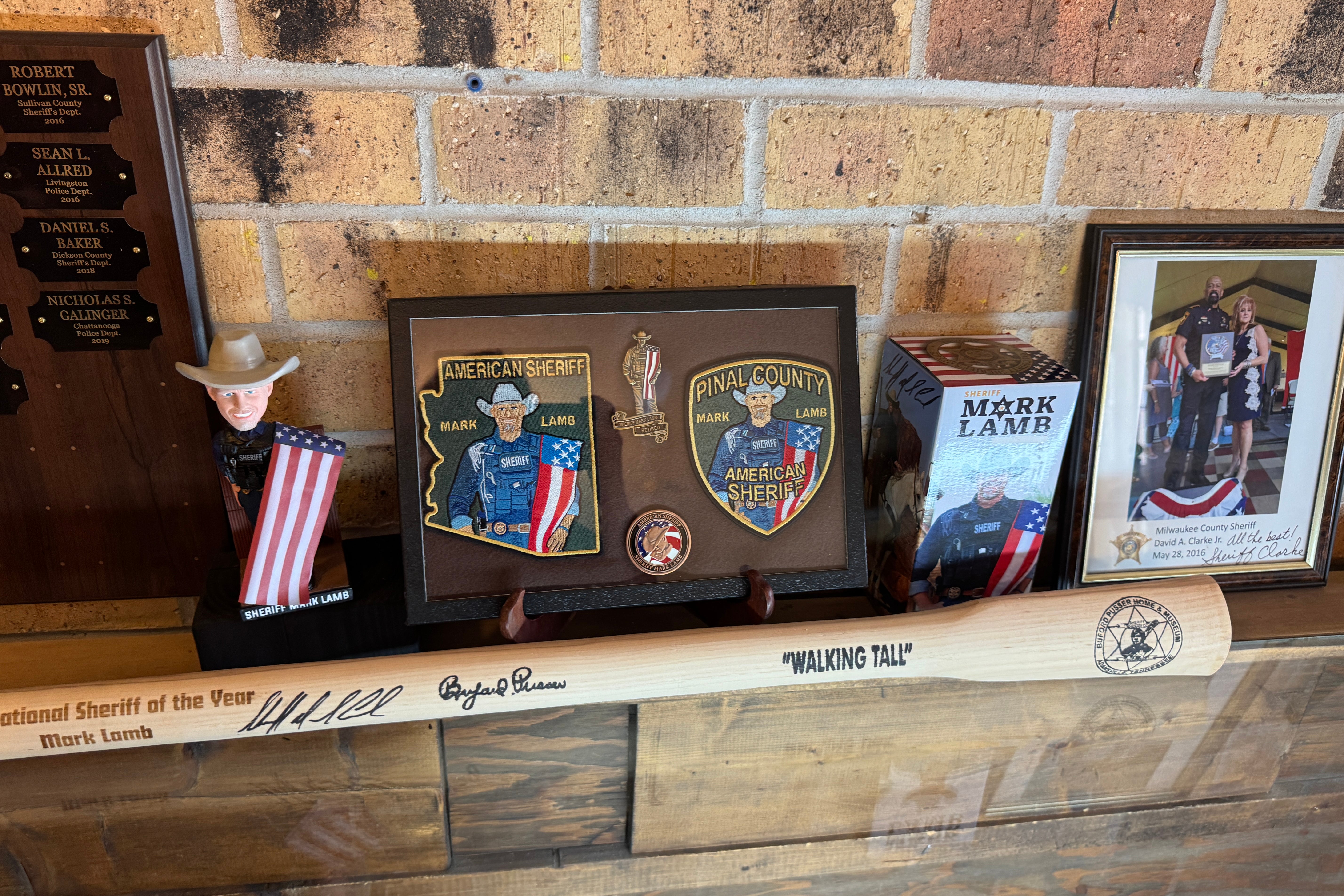 Memorabilia scattered across a mantel, including a wooden bat and patches labeled "America's Sheriff."