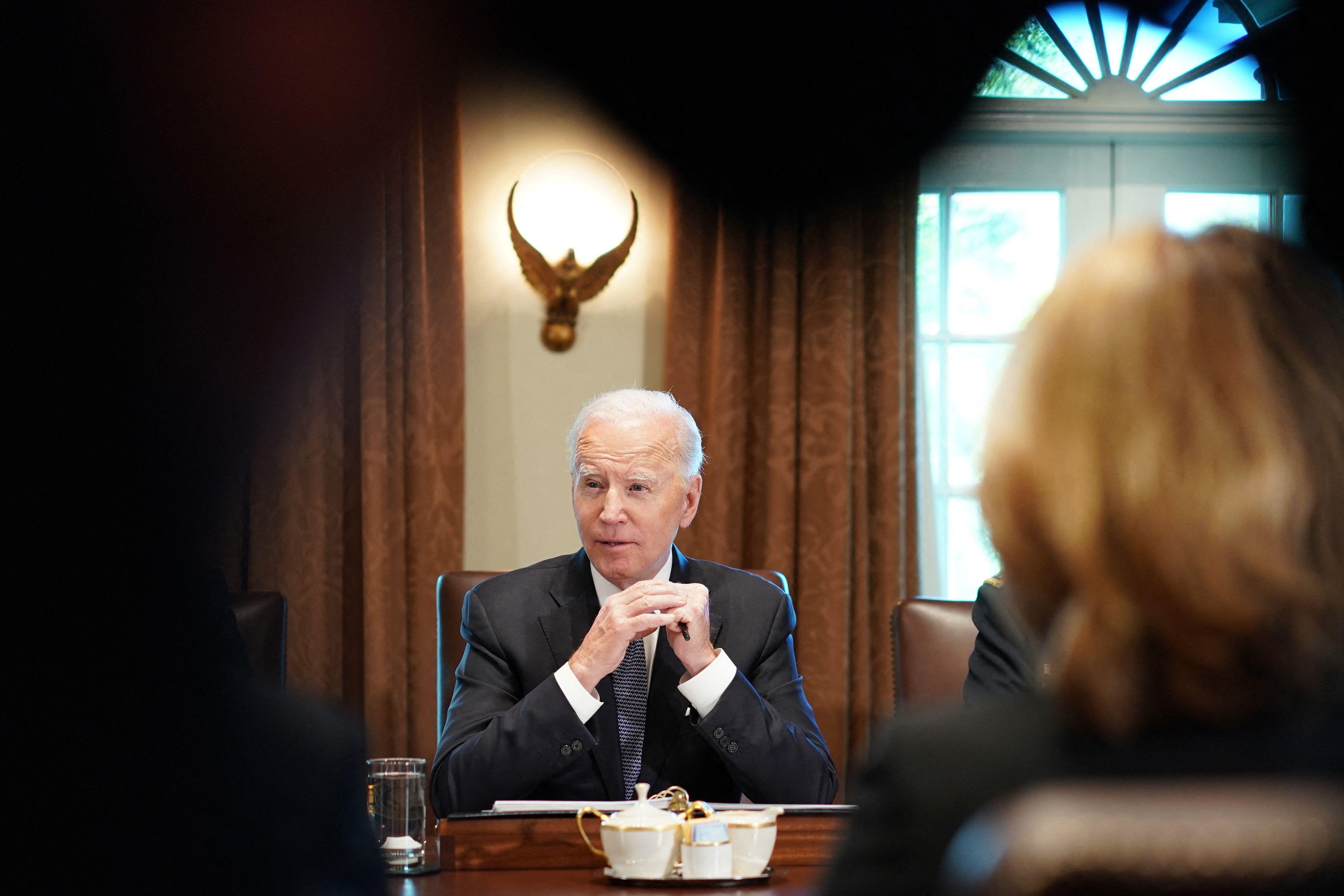 A photo of President Joe Biden that is framed by shadows, and a lamp above him.
