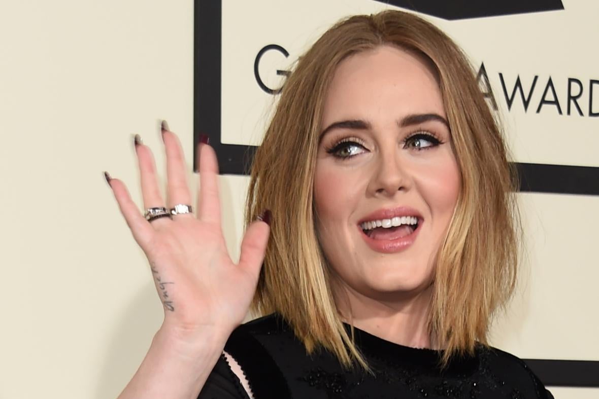 Adele smiles and waves on the red carpet
