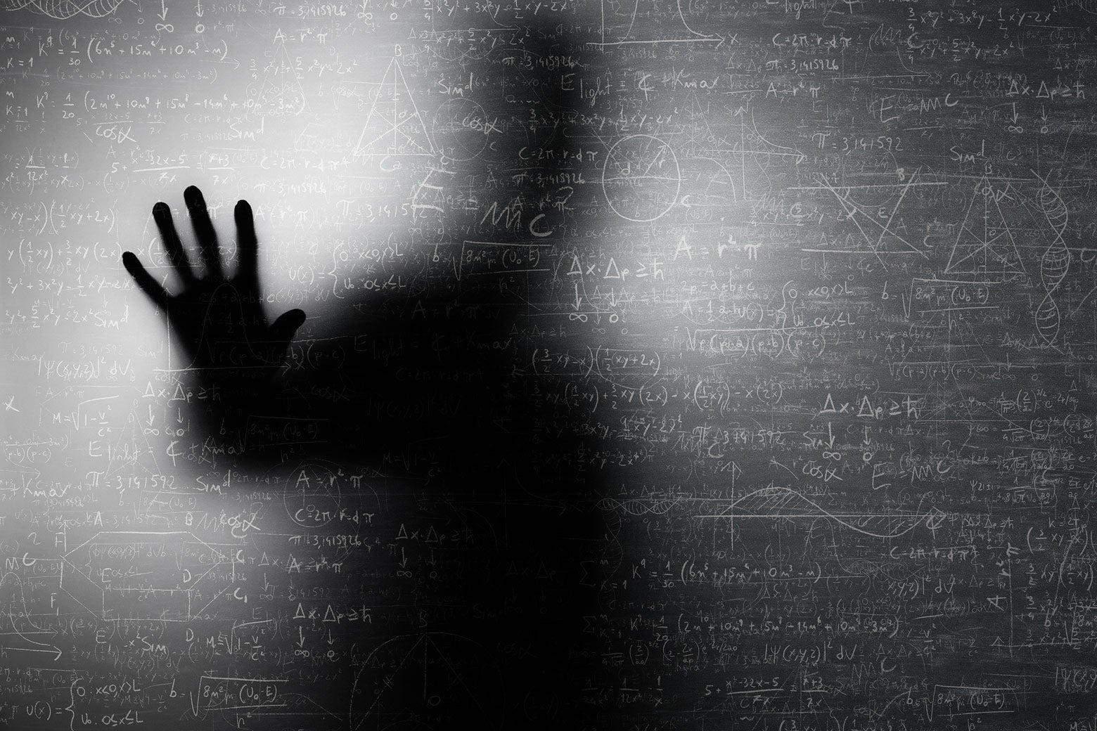The silhouette of a male scientist, looking menacing as he touches a board filled with equations.