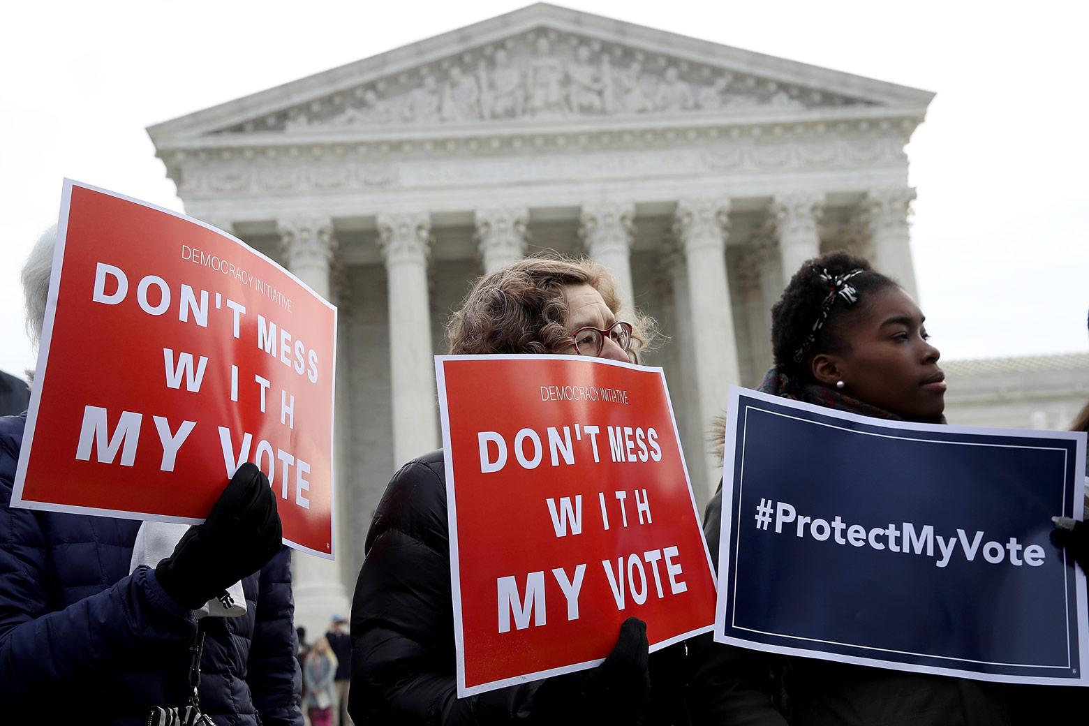 Three protesters hold signs saying “Don’t Mess With My Vote” and “#ProtectMyVote” on Wednesday in front of the Supreme Court building in Washington. Photo by Win McNamee/Getty Images.