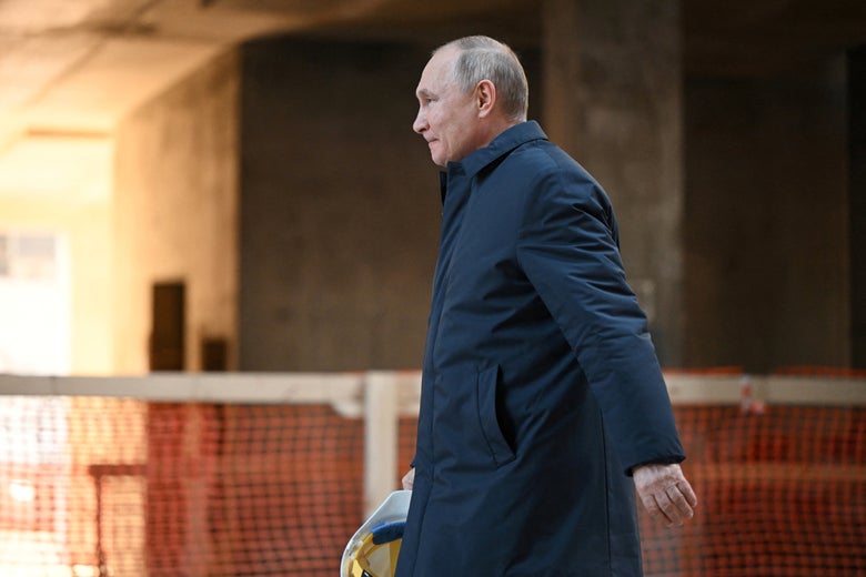 Vladimir Putin in a long coat striding outside