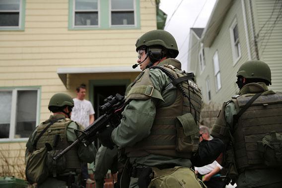 Members of a police SWAT team conduct a door-to-door search for 19-year-old Boston Marathon bombing suspect Dzhokhar A. Tsarnaev on April 19, 2013 in Watertown, Mass.