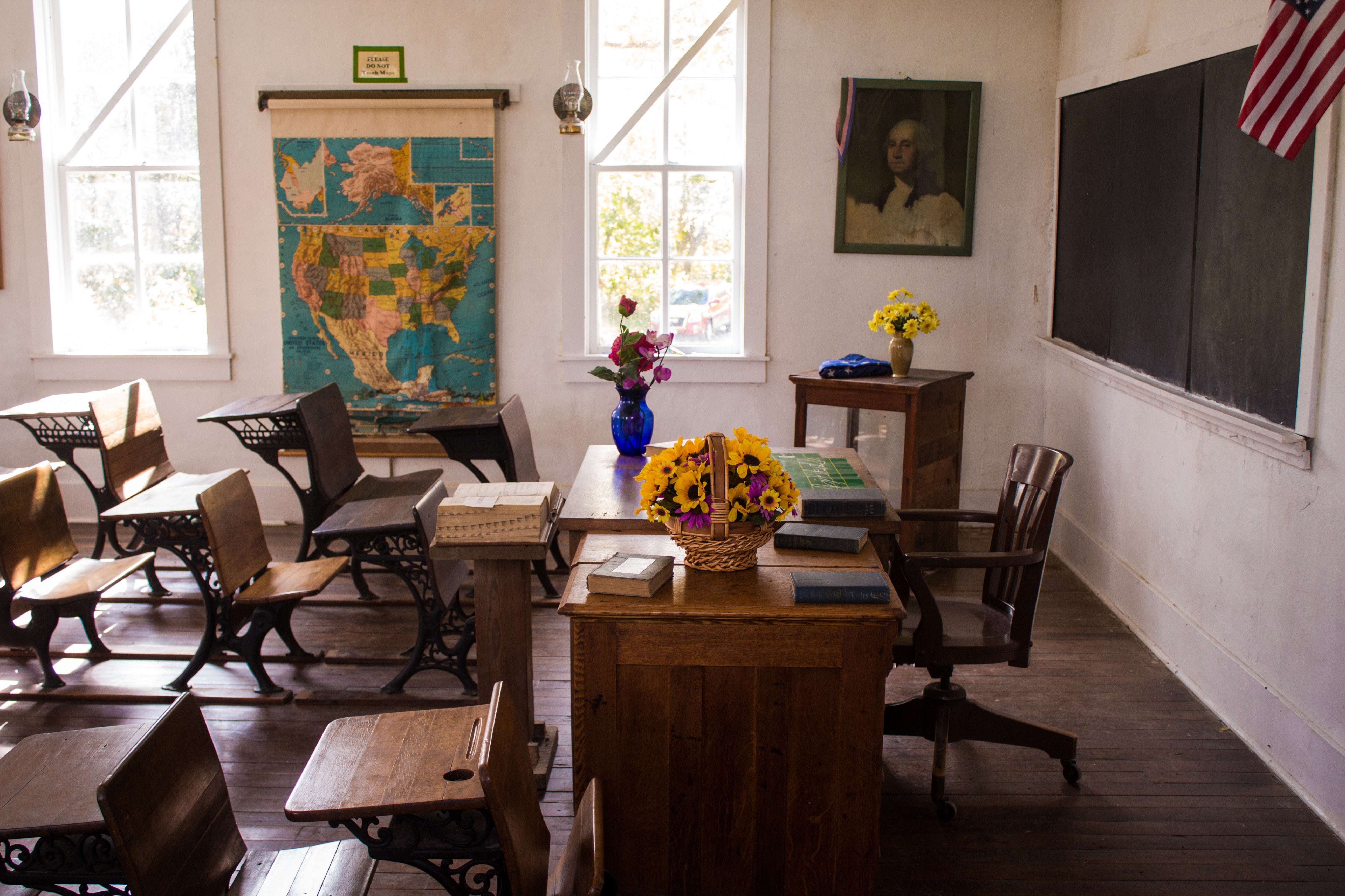 A classroom with a U.S. map on the wall and an American flag above the blackboard.