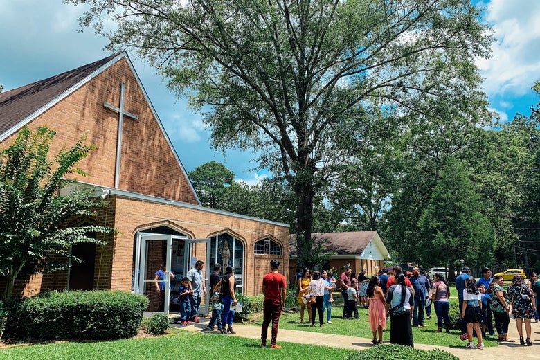 A crowd of congregants gathered outside the church on a sunny day.