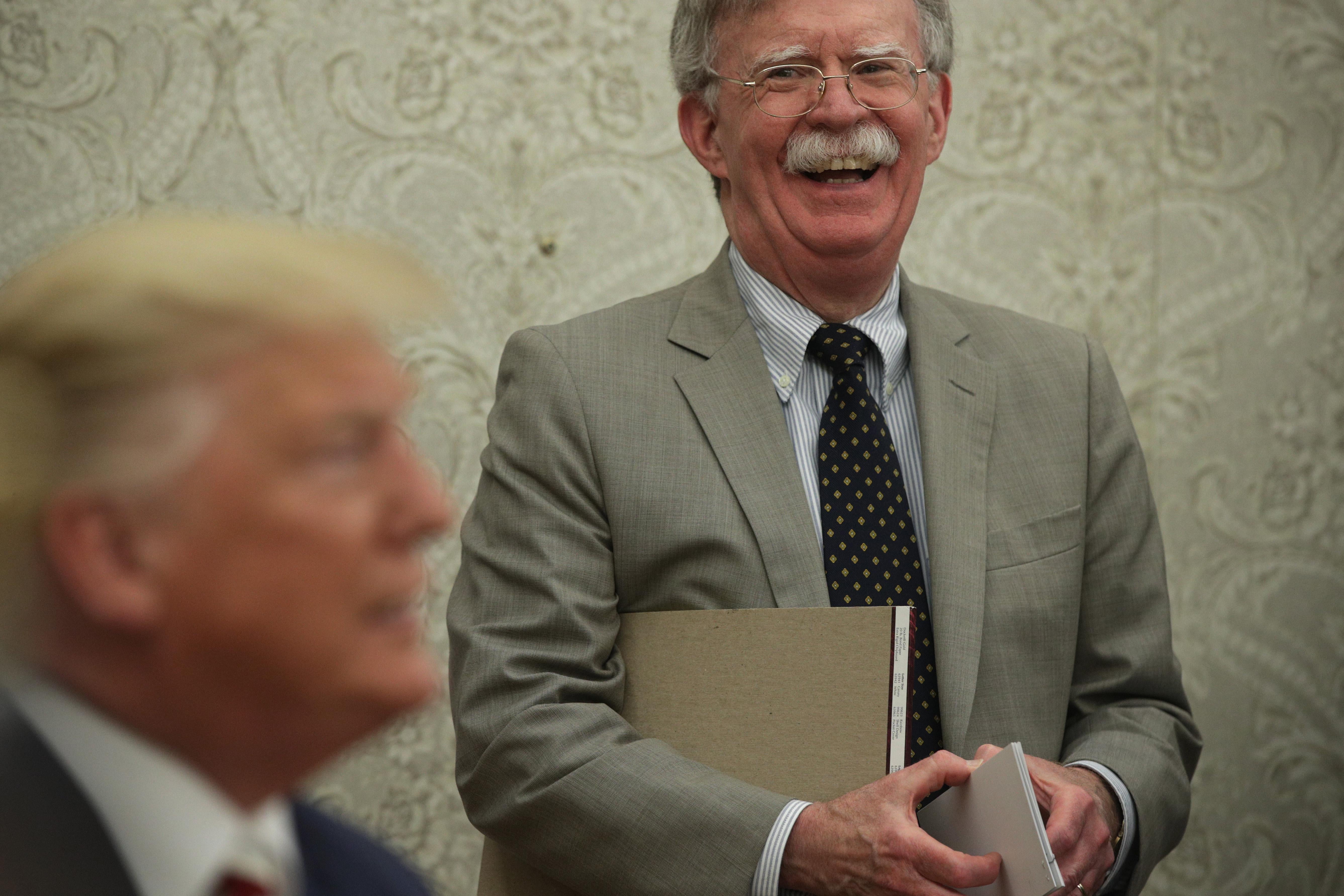 President Donald Trump speaks to members of the media as John Bolton listens at the Oval Office of the White House on August 20, 2019 in Washington, D.C. 