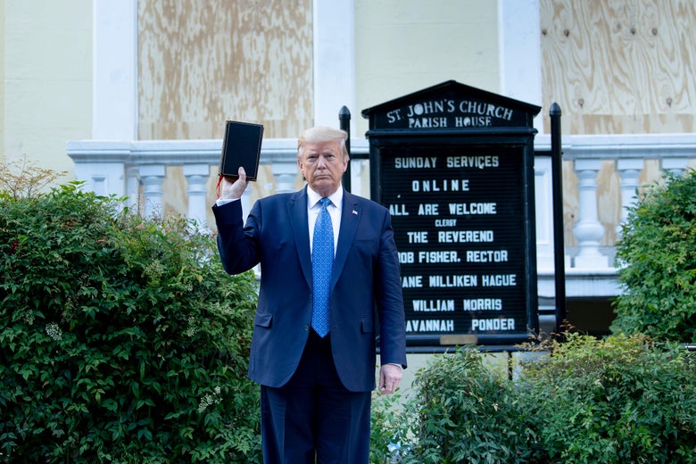 Trump, standing in front of the church, holds up a Bible with one hand.