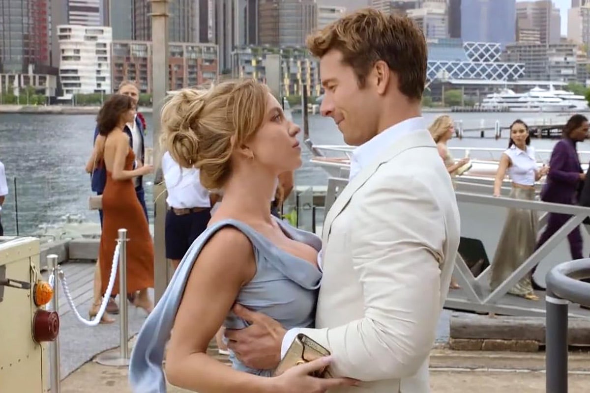 Glen Powell and Sydney Sweeney embrace each other on a pier.