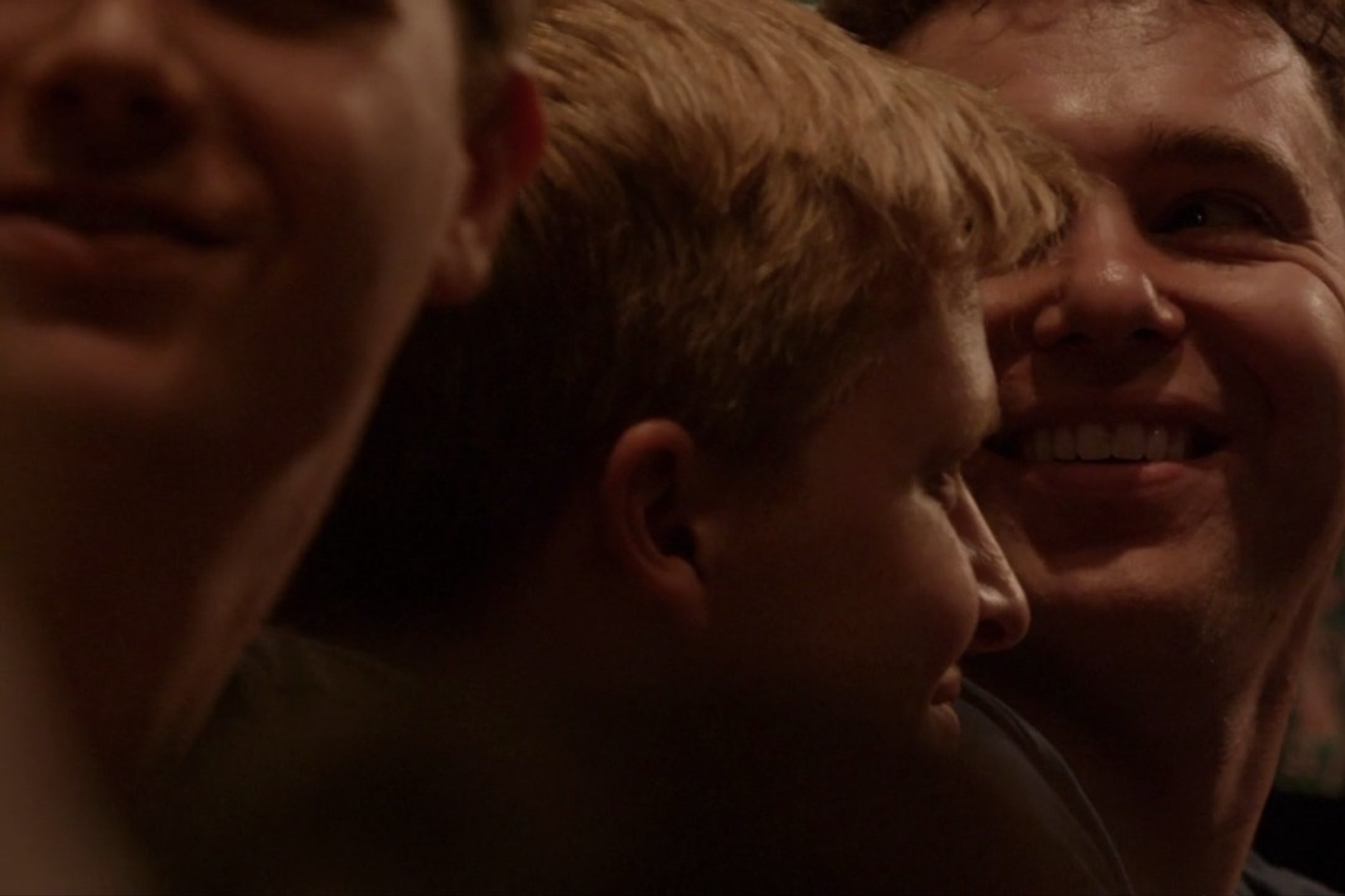 Ronan Farrow and Jon Lovett, sitting in a theater audience. Lovett is smiling widely.